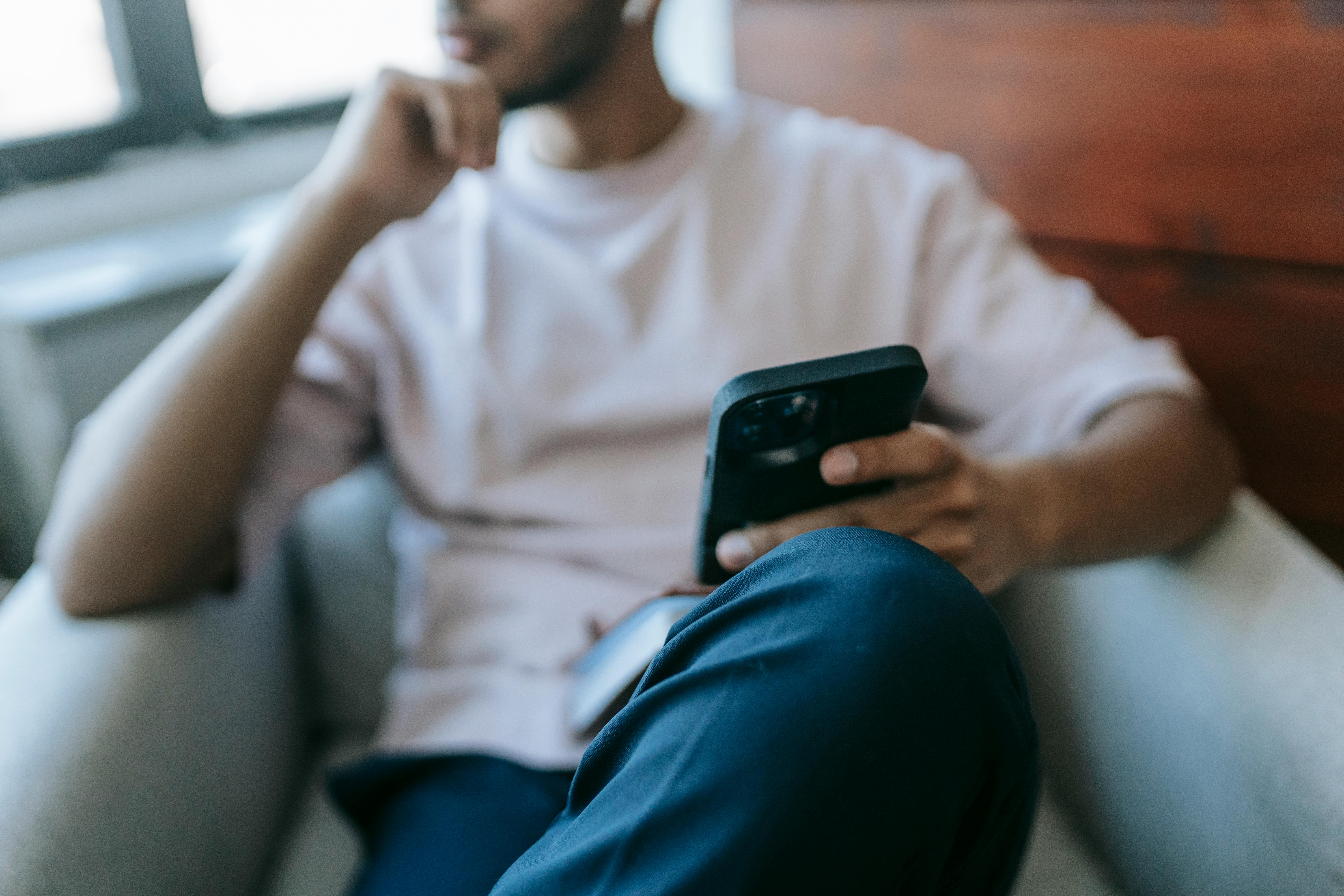 Ein Mann, der tief in Gedanken versunken sein Telefon in der Hand hält | Quelle: Pexels
