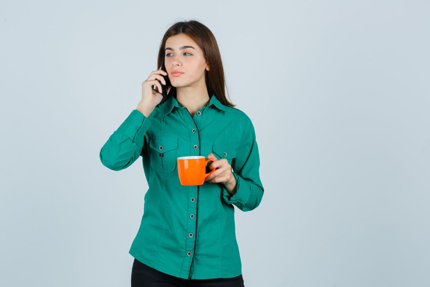 Eine Frau telefoniert, während sie eine orangefarbene Tasse hält | Quelle: Freepik