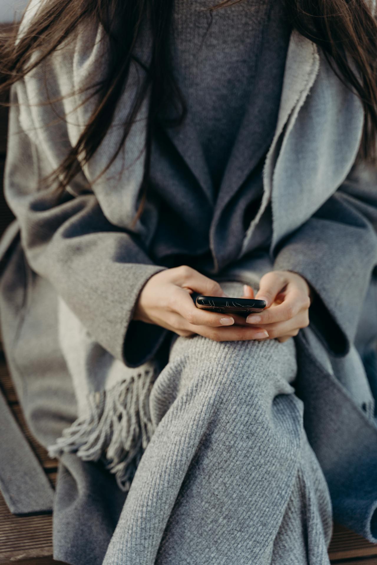 Eine Frau in grauer Jacke hält ihr Telefon | Quelle: Pexels