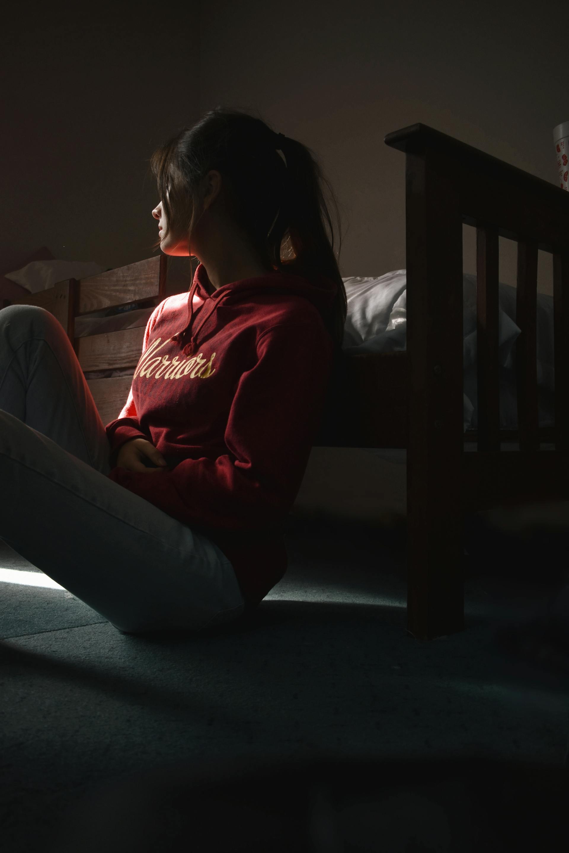 Eine junge Frau, die auf dem Boden sitzt und zur Seite schaut | Quelle: Pexels