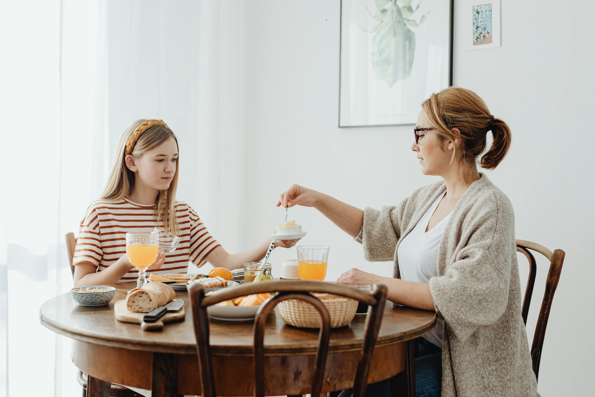 Eine Frau und ein Mädchen im Teenageralter sitzen am Esstisch | Quelle: Pexels
