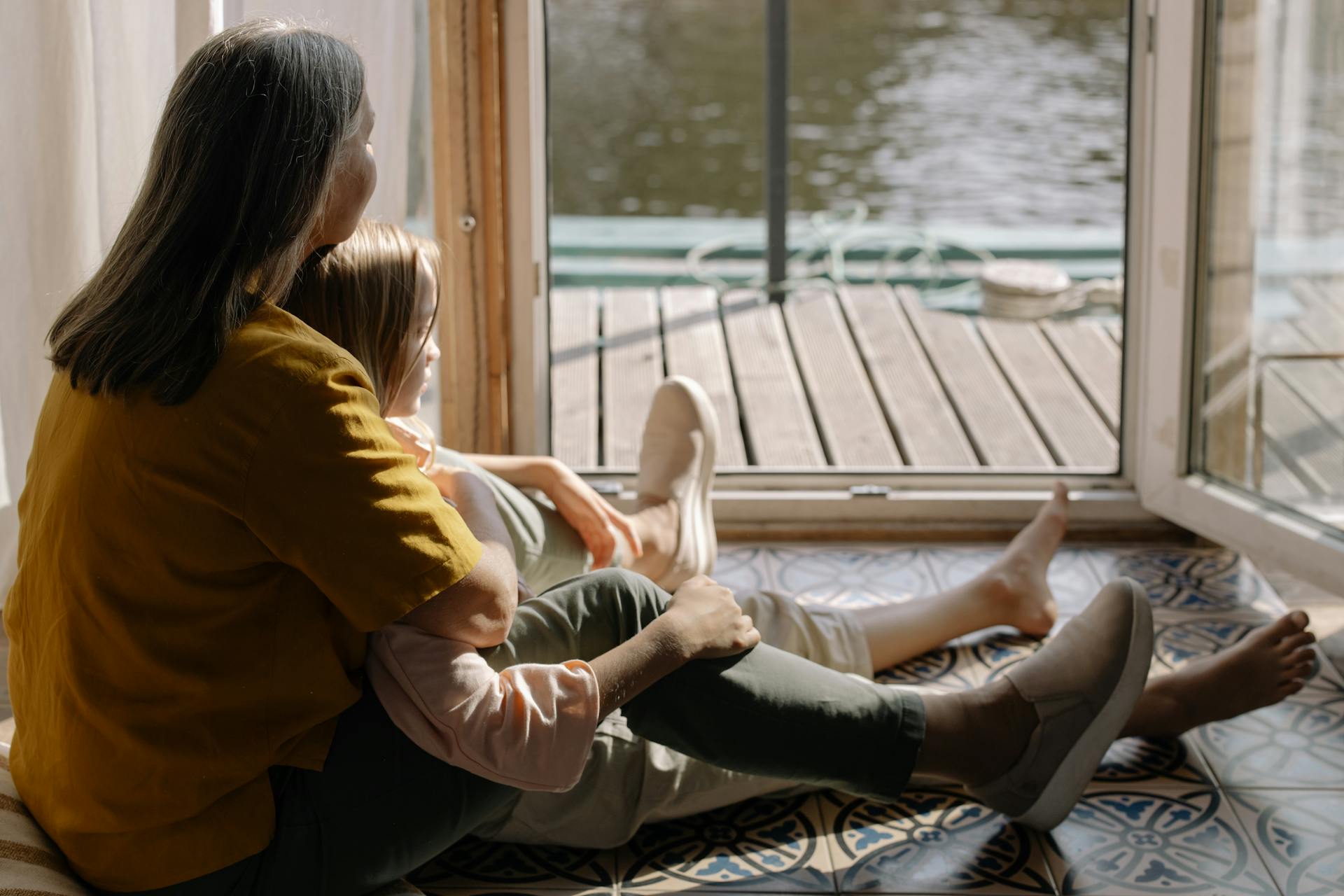 Eine Oma sitzt mit ihrer Enkelin auf dem Boden und schaut nach draußen | Quelle: Pexels