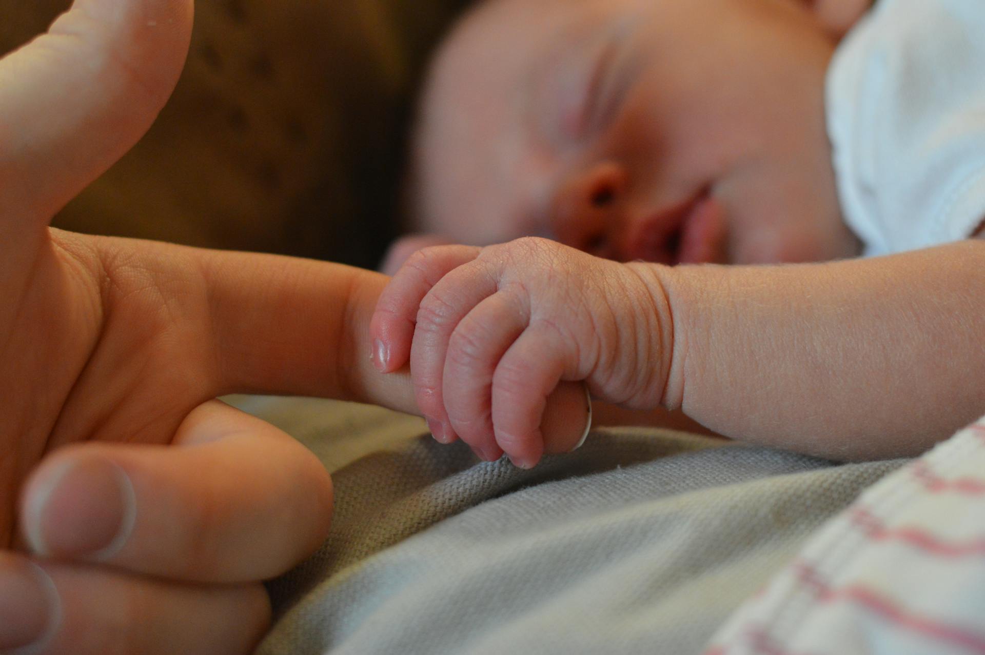 Ein Baby, das den Finger eines Menschen hält | Quelle: Pexels