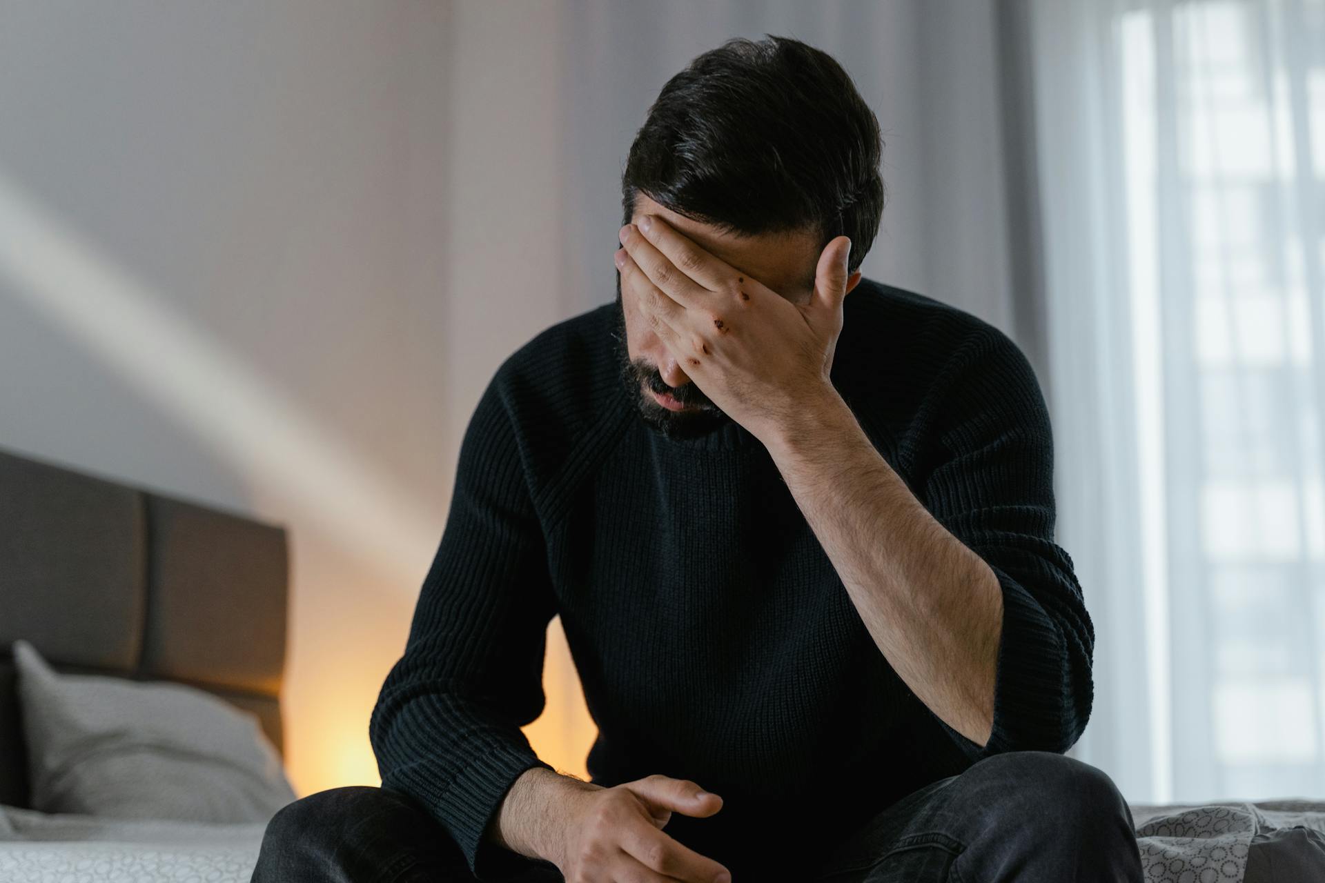 Eine Nahaufnahme eines verzweifelten Mannes, der auf dem Bett sitzt | Quelle: Pexels