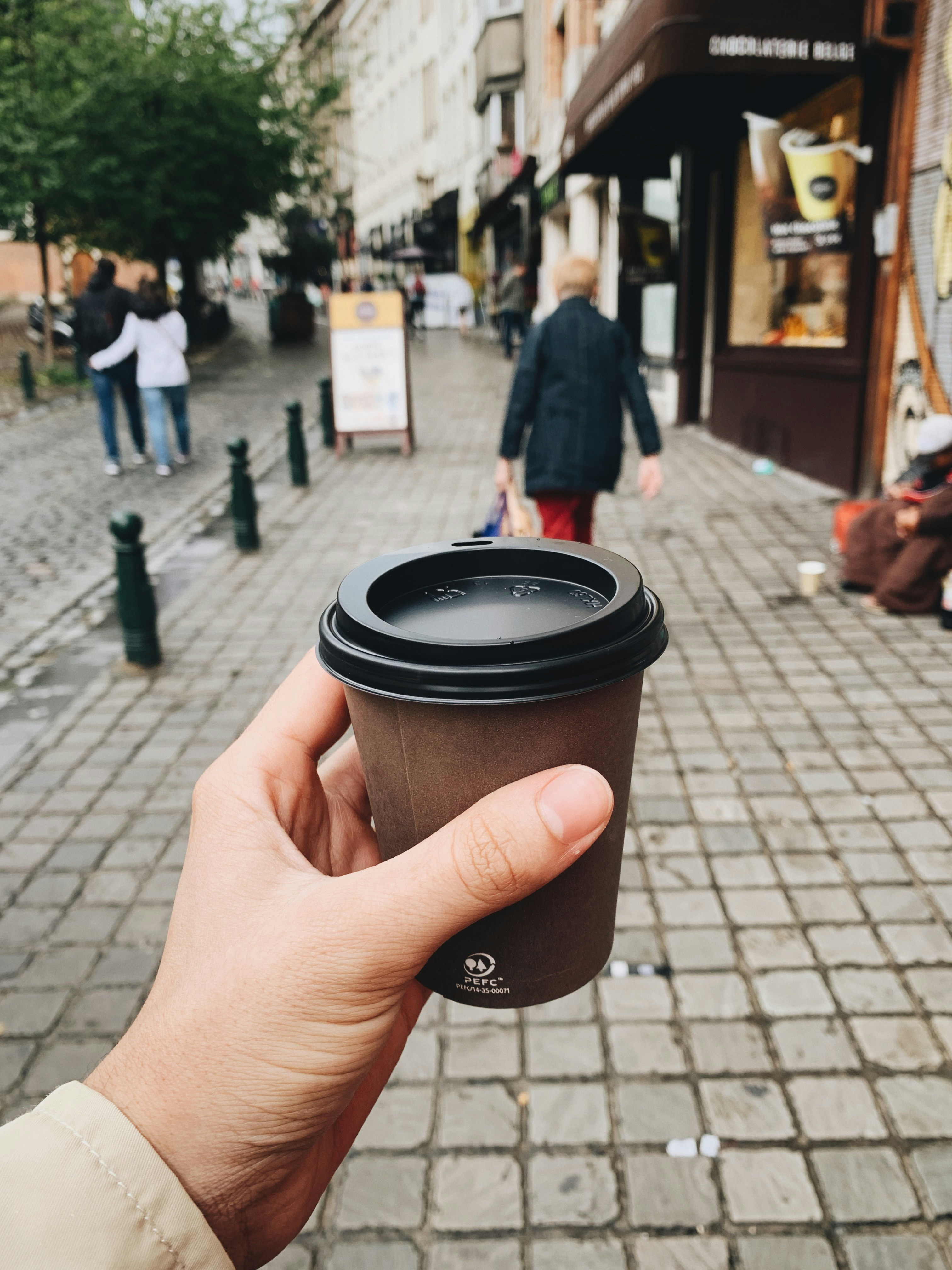 Eine Person hält einen Kaffeebecher zum Mitnehmen | Quelle: Unsplash