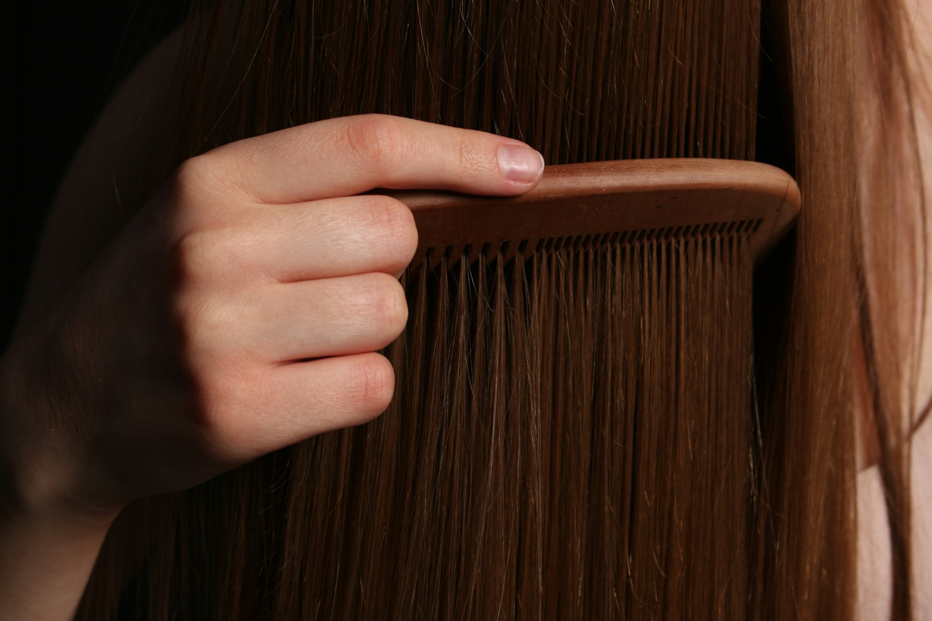 Eine Person beim Kämmen langer Haare | Quelle: Unsplash