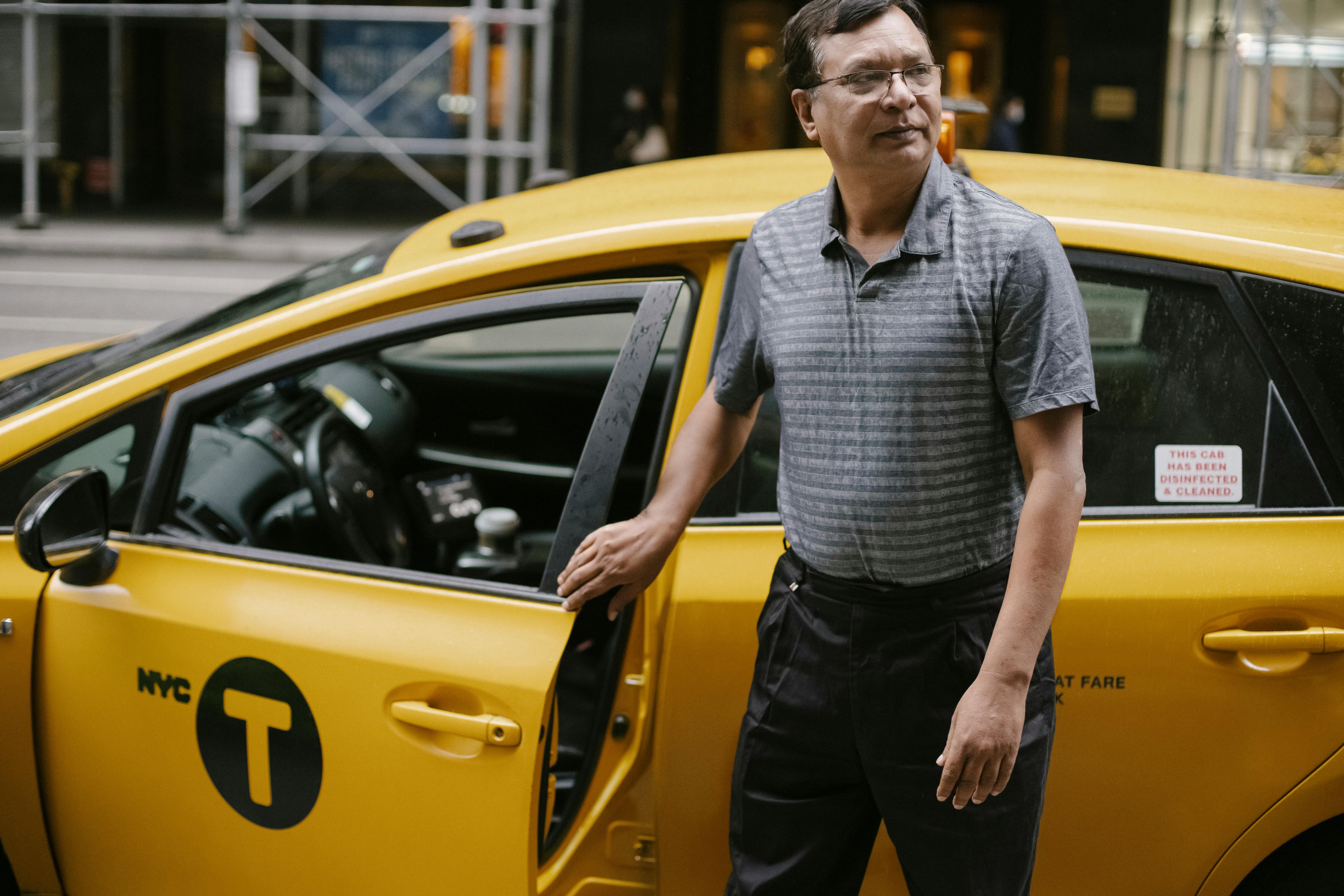 Ein Taxifahrer, der neben seinem Auto steht | Quelle: Pexels
