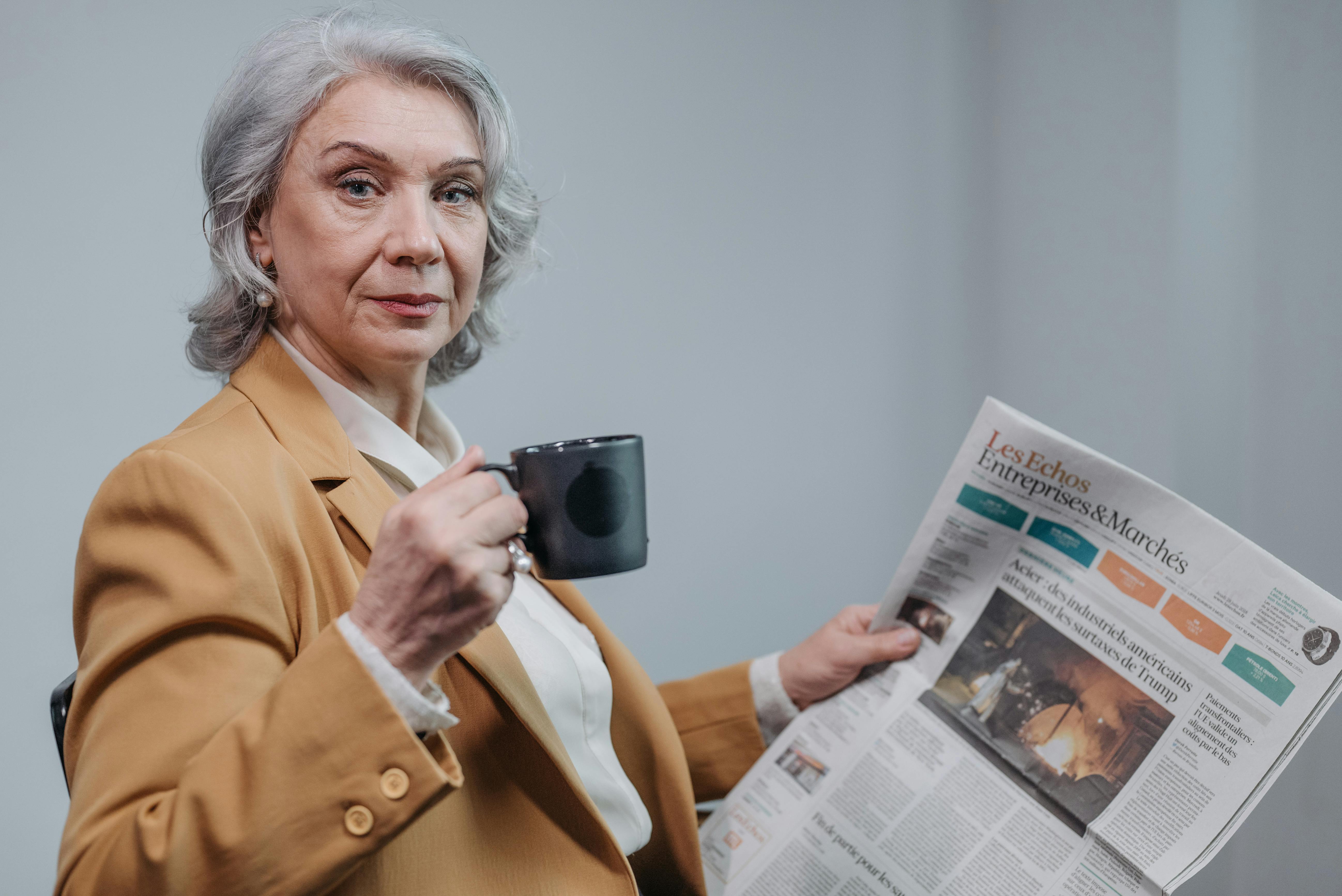 Eine ernste Frau trinkt Kaffee und liest eine Zeitung | Quelle: Pexels