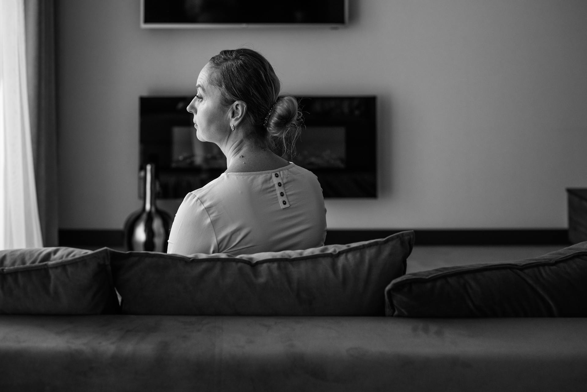 Graustufenaufnahme einer traurigen Frau, die in einem Raum sitzt | Quelle: Pexels