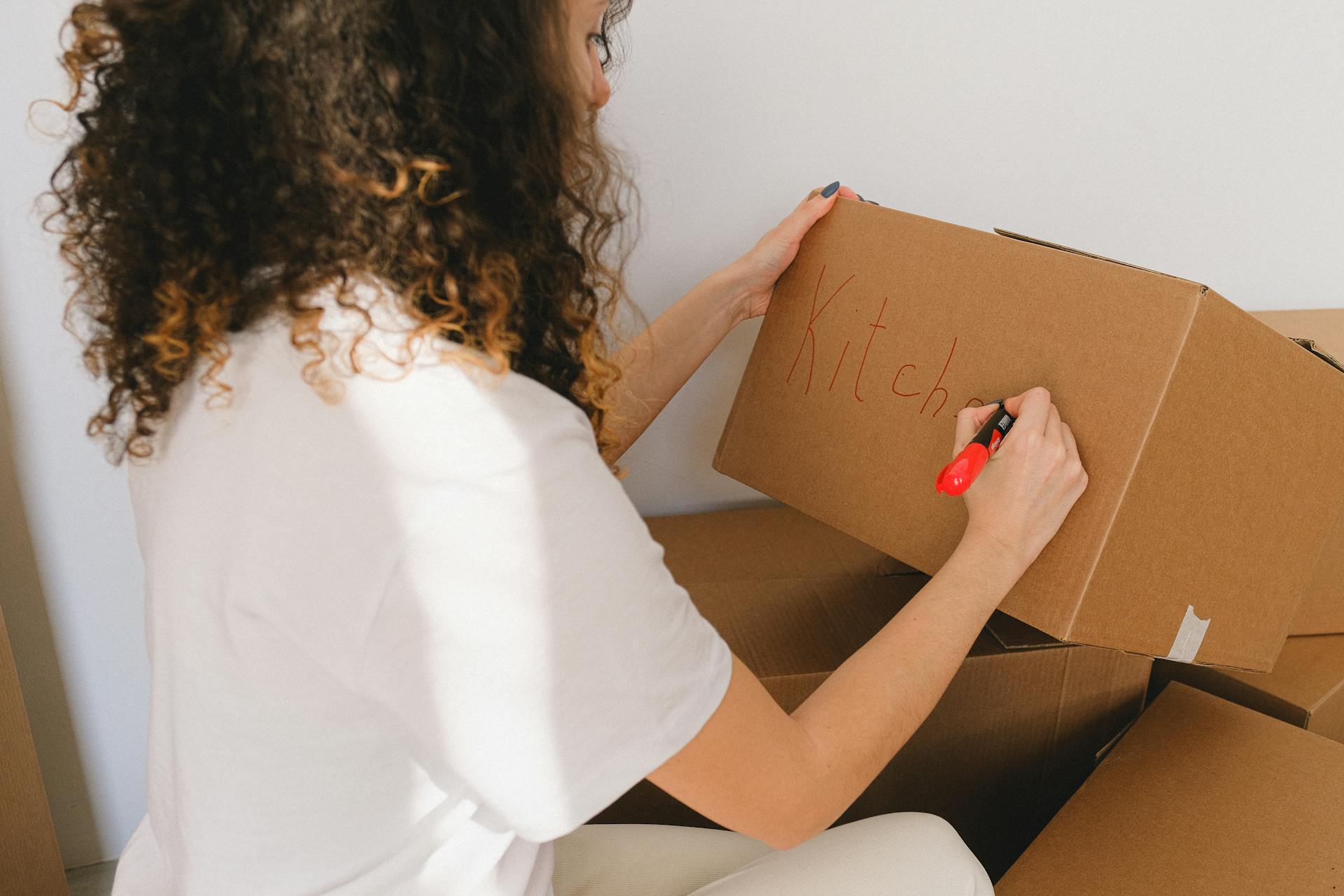 Eine Frau beschriftet eine Kiste | Quelle: Pexels