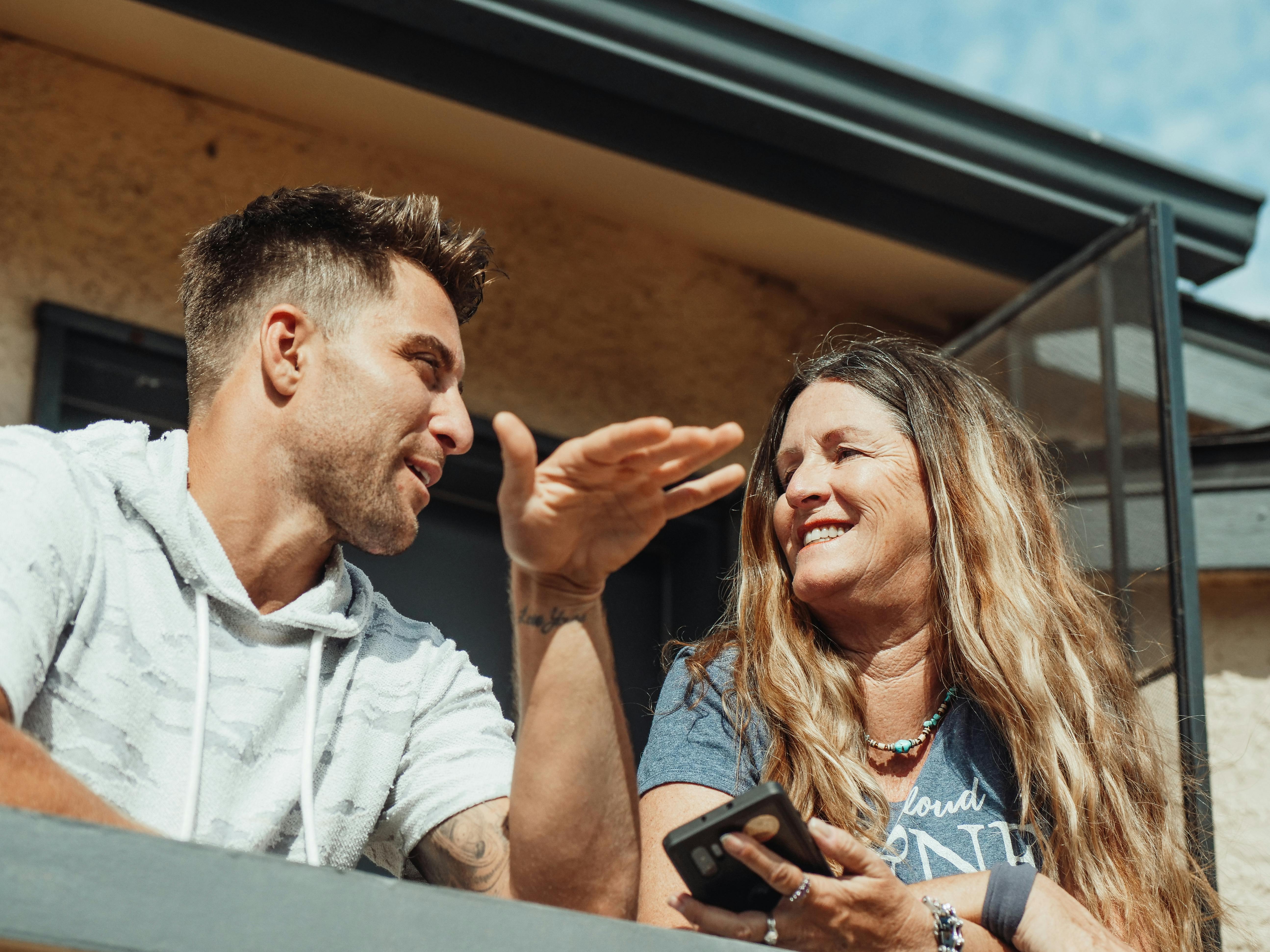 Ältere Frau im Gespräch mit ihrem Sohn auf einem Balkon | Quelle: Pexels