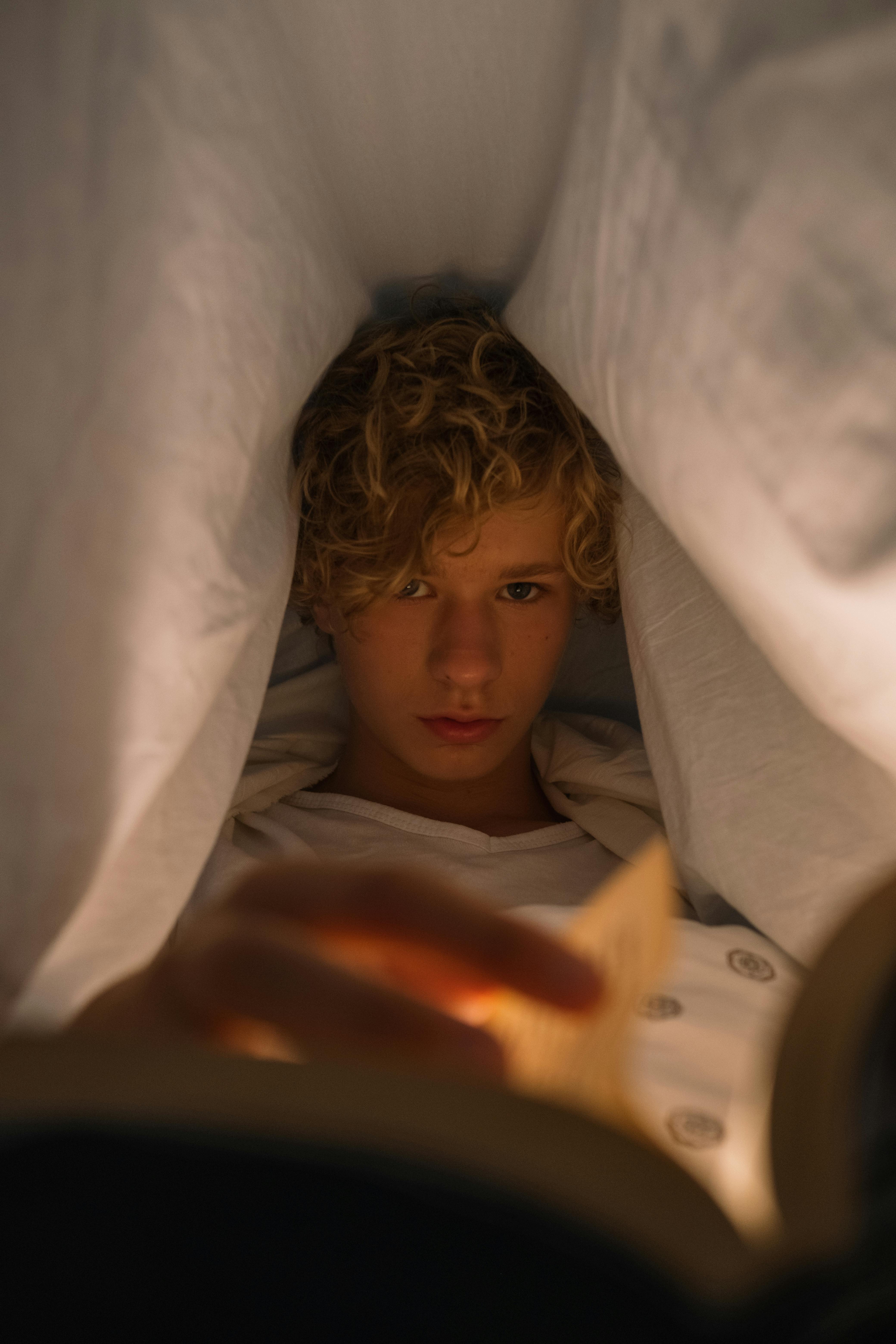 Teenager liest nachts unter dem Bettlaken | Quelle: Pexels