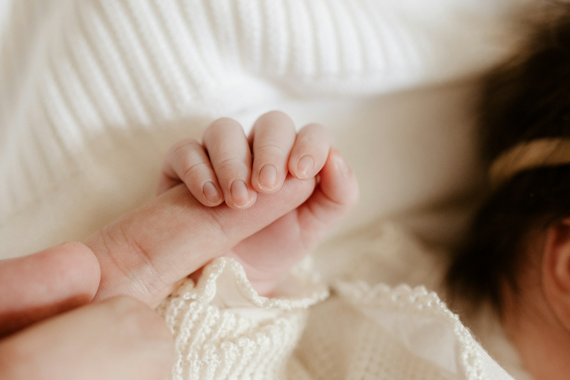 Ein Baby, das den Finger eines Menschen hält | Quelle: Unsplash