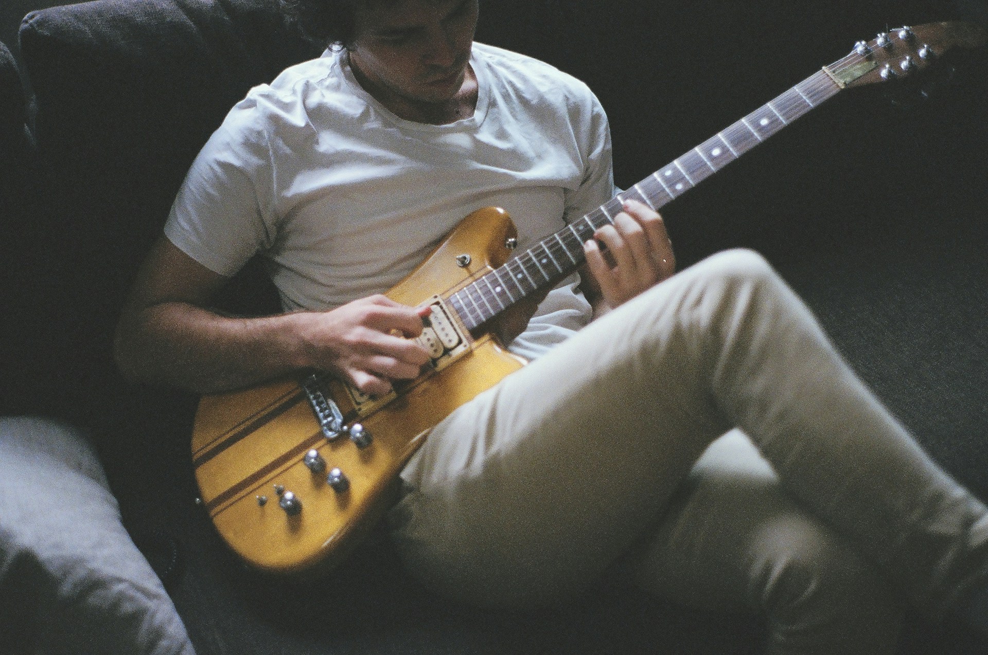 Ein Mann spielt eine E-Gitarre auf einem Sofa | Quelle: Unsplash