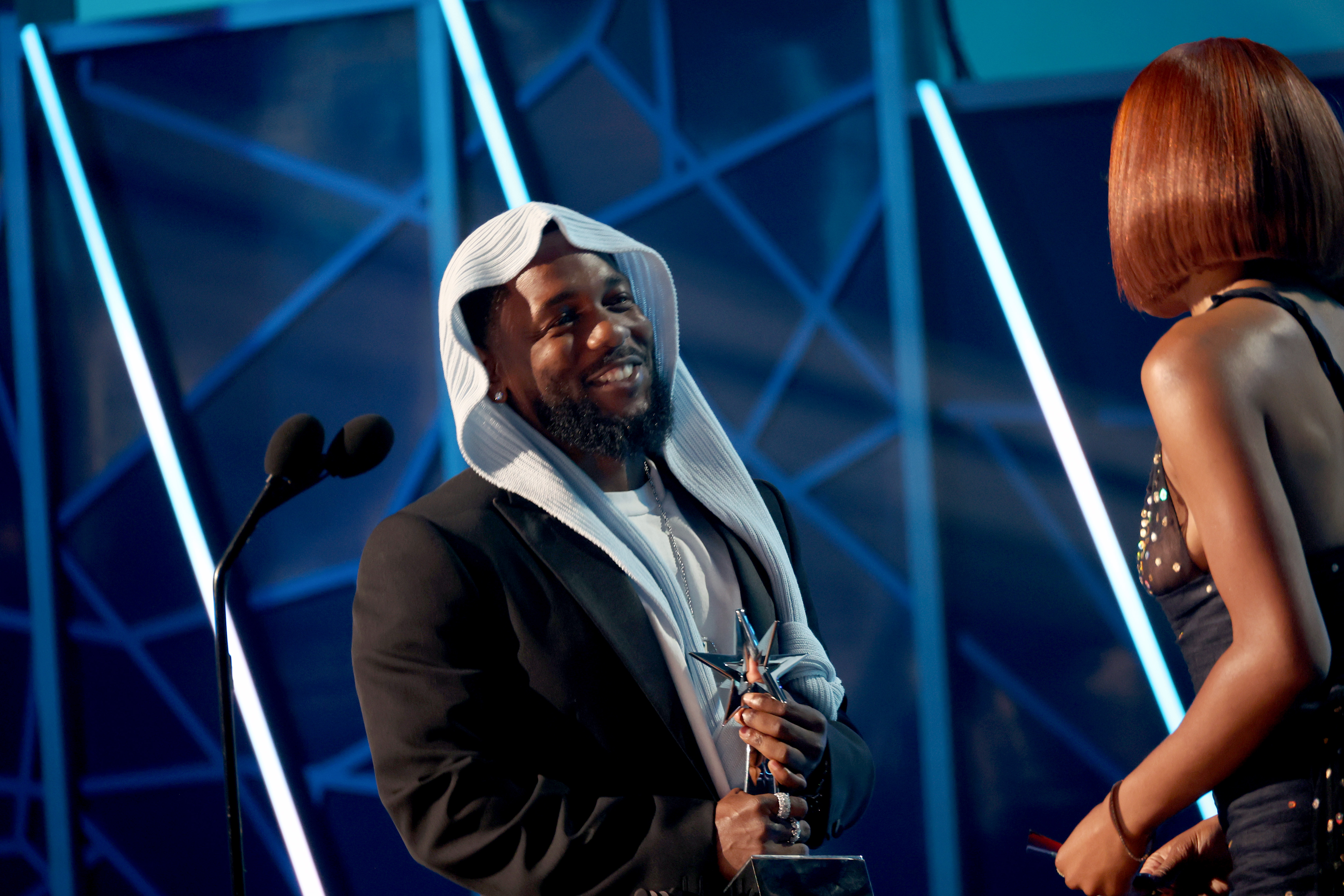 Strahlend nimmt Kendrick Lamar bei den BET Awards 2025 einen Preis entgegen und unterhält sich fröhlich mit Keke Palmer. Die einzigartige Kopfbedeckung des Rappers und seine zahlreichen Preise machten ihn zu einem der meistdiskutierten Stars des Abends.