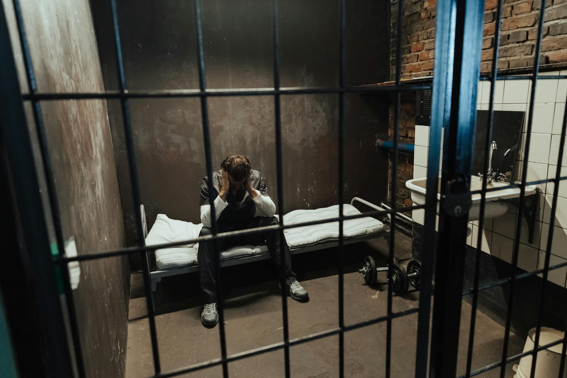 Ein Mann sitzt auf einem Bett hinter Gittern | Quelle: Pexels