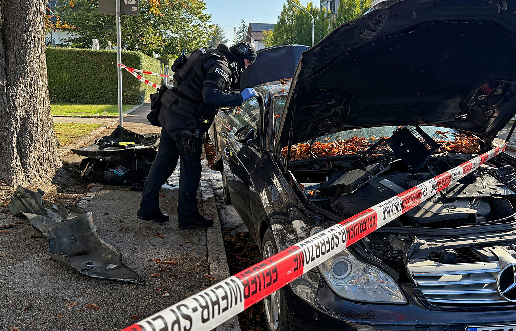 01. Oktober 2025, Bayern, München: Ein Polizist in Schutzweste steht an einem in Brand geratenen Auto. Ein Brand in einem Einfamilienhaus in München hat einen Großeinsatz von Polizei und Feuerwehr ausgelöst. | Quelle: Getty Images
