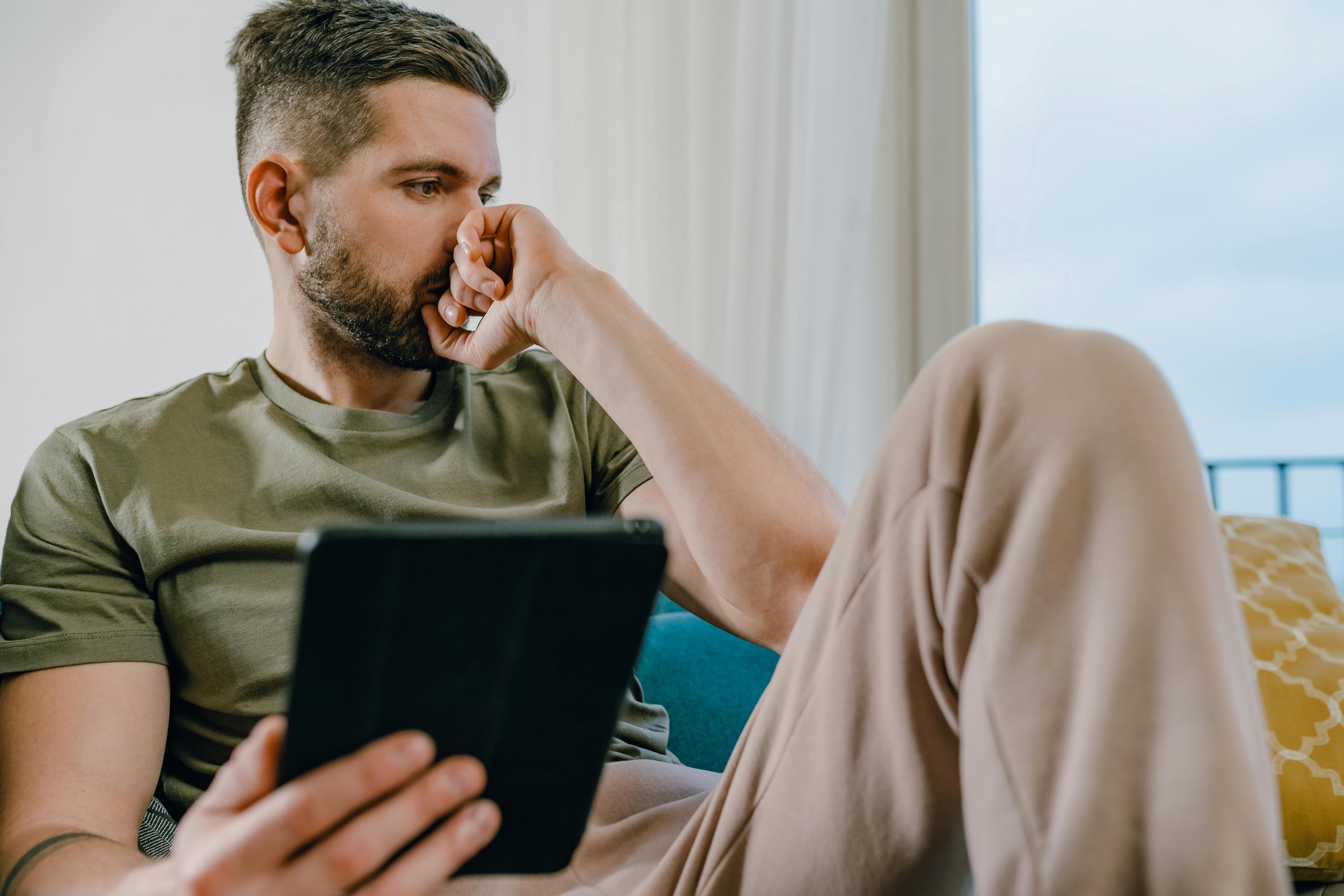 Ein Mann, der in Gedanken versunken ein Tablet hält | Quelle: Pexels