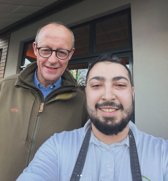 Bundeskanzler Friedrich Merz mit einem Angestellten des R-Cafés Neheim | Quelle: instagram.com/p/DUgQ5tqDAUL/?utm_source=ig_embed&ig_rid=15464661-c9da-4ca9-bbea-1ec7dd8e1813&img_index=2