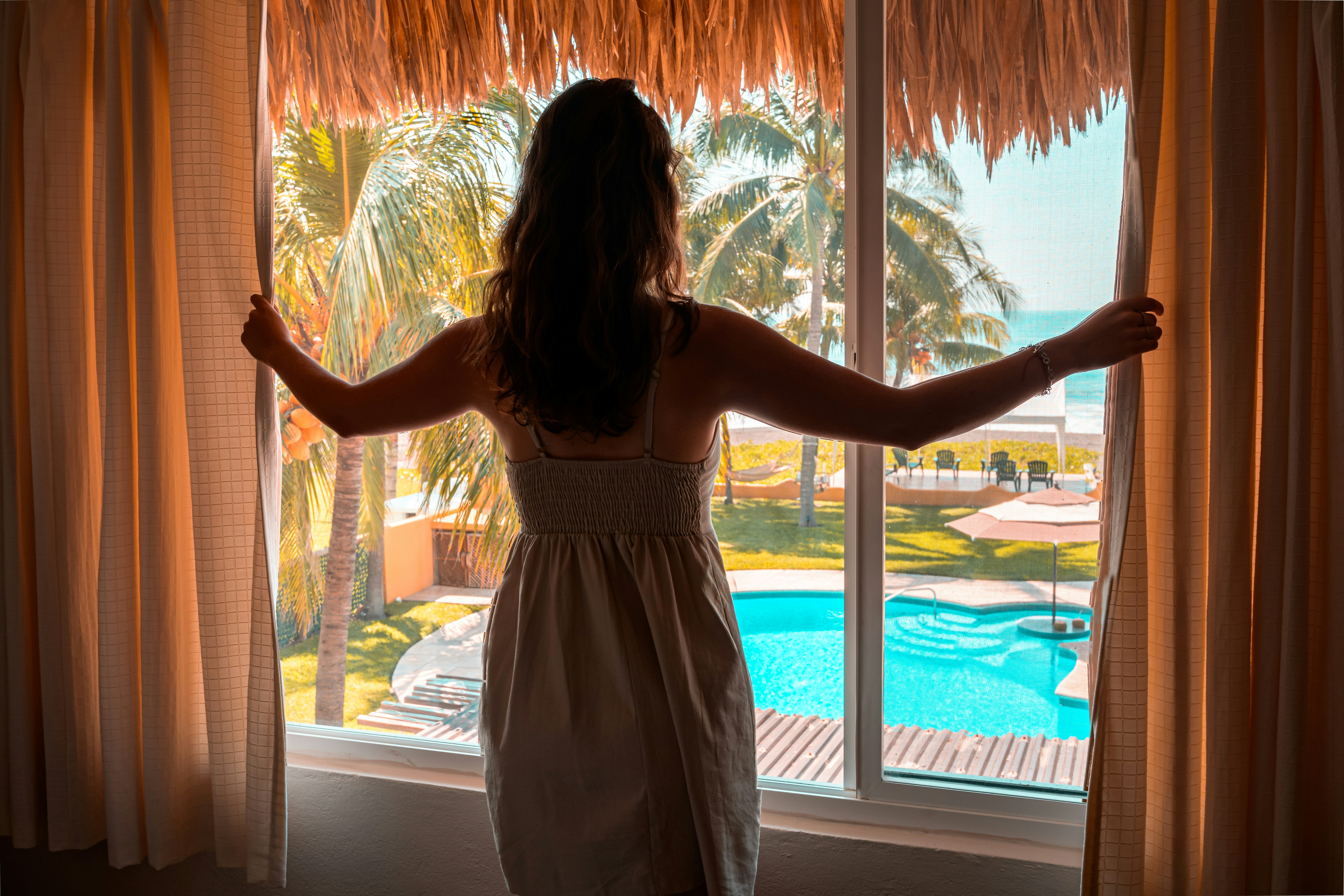 Eine Person, die an einem Fenster in einem Hotelzimmer steht | Quelle: Unsplash