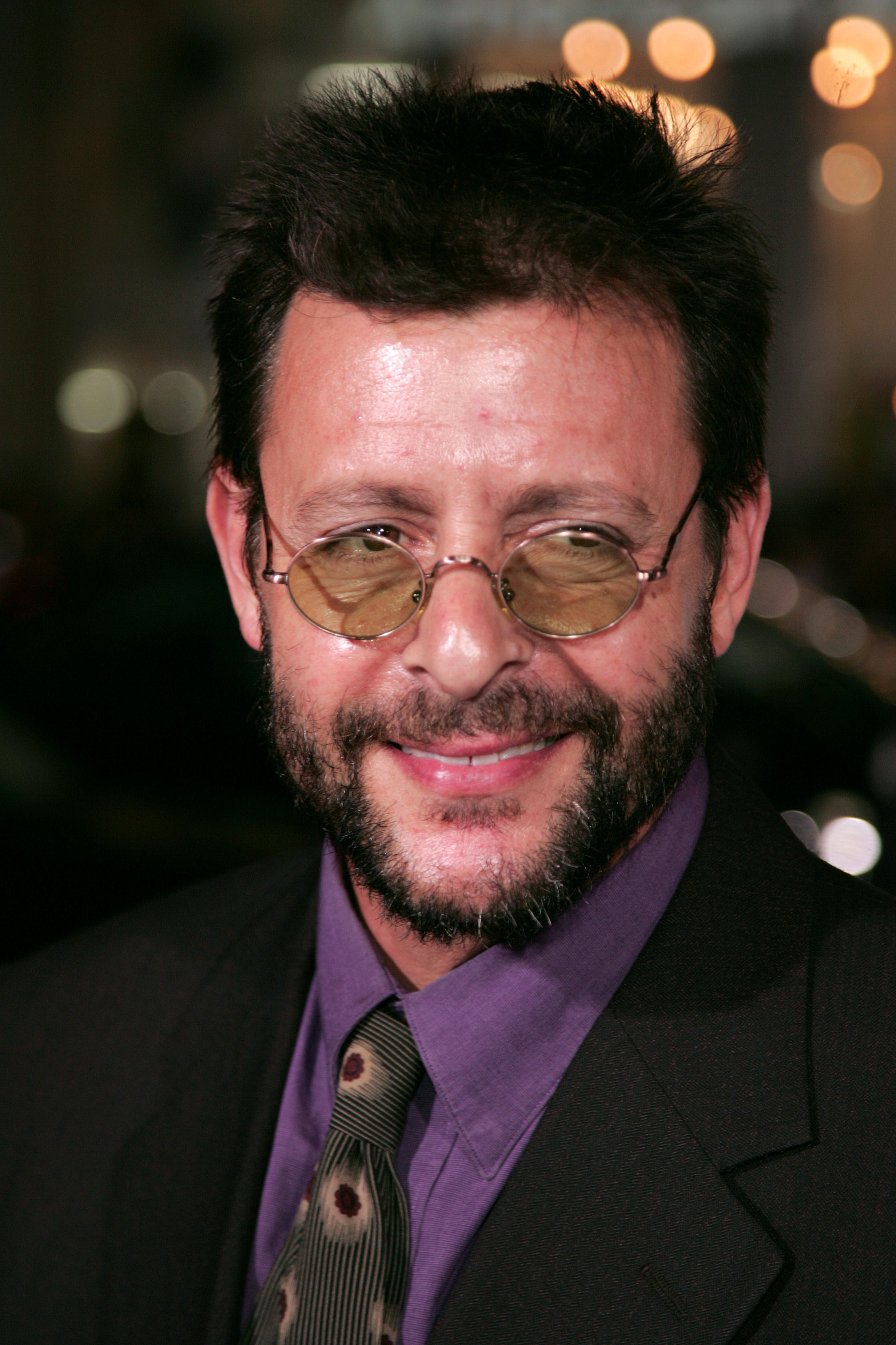 Mit einer kleinen runden getönten Brille, einem Vollbart und einem lila Hemd mit Kragen sowie einer gemusterten Krawatte lächelte der Schauspieler herzlich, als er am Grauman’s Chinese Theatre zur Hollywood-Premiere von