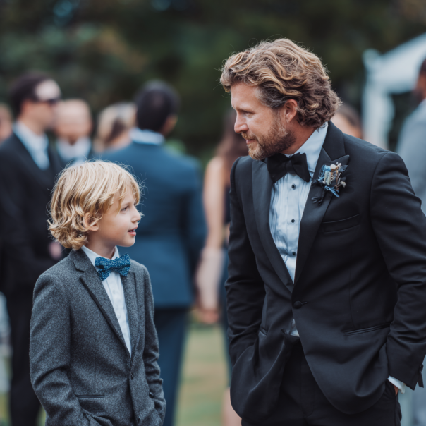 Ein Vater und sein Sohn unterhalten sich auf einer Hochzeit | Quelle: Midjourney
