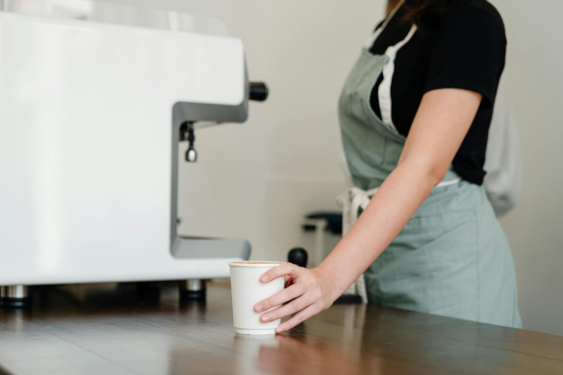 Eine Kellnerin steht neben einer Kaffeemaschine | Quelle: Pexels