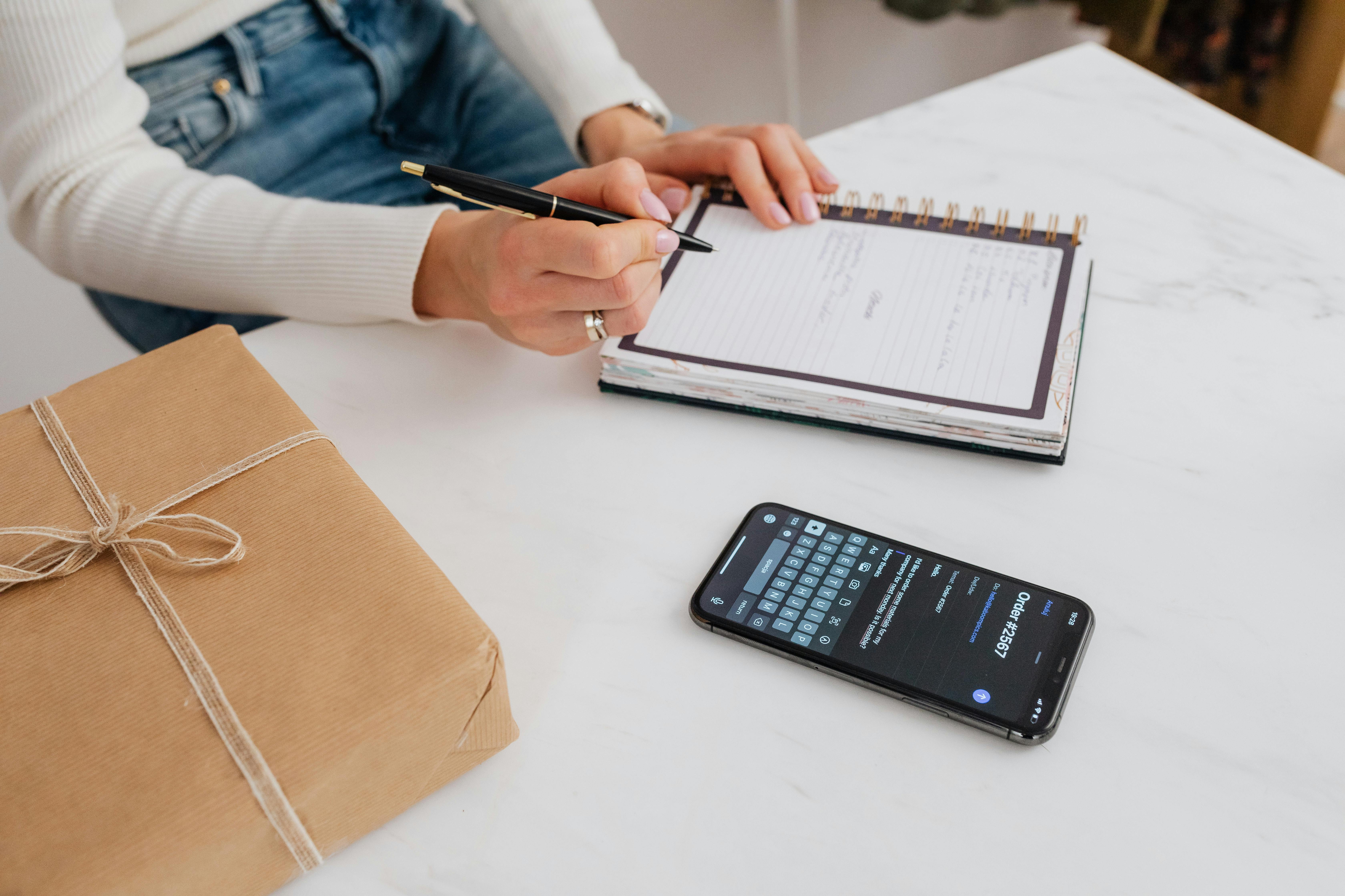 Eine Person, die auf ein weißes Notizbuch schreibt | Quelle: Pexels