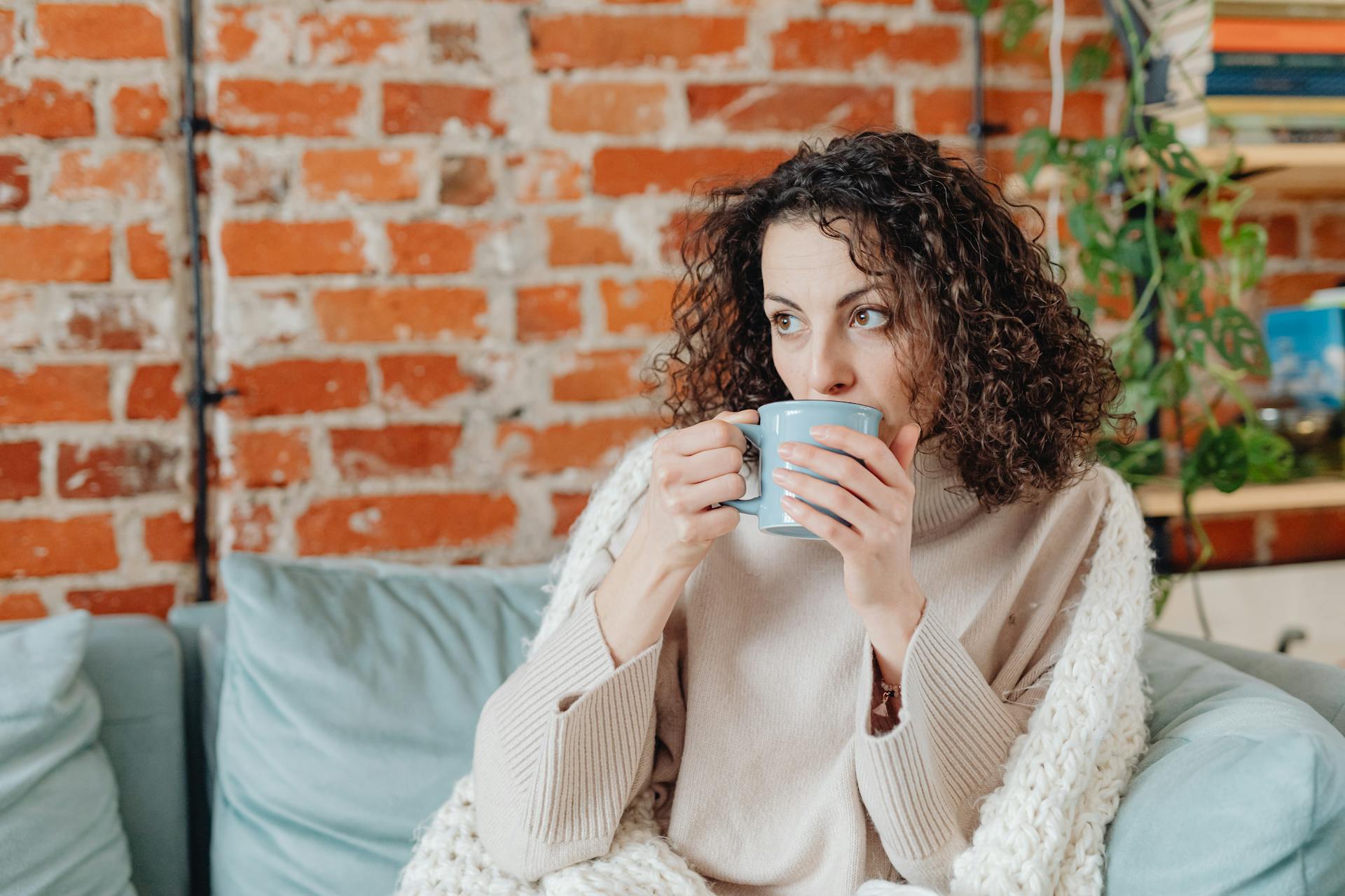 Eine Frau trinkt ein warmes Getränk auf einer Couch | Quelle: Pexels