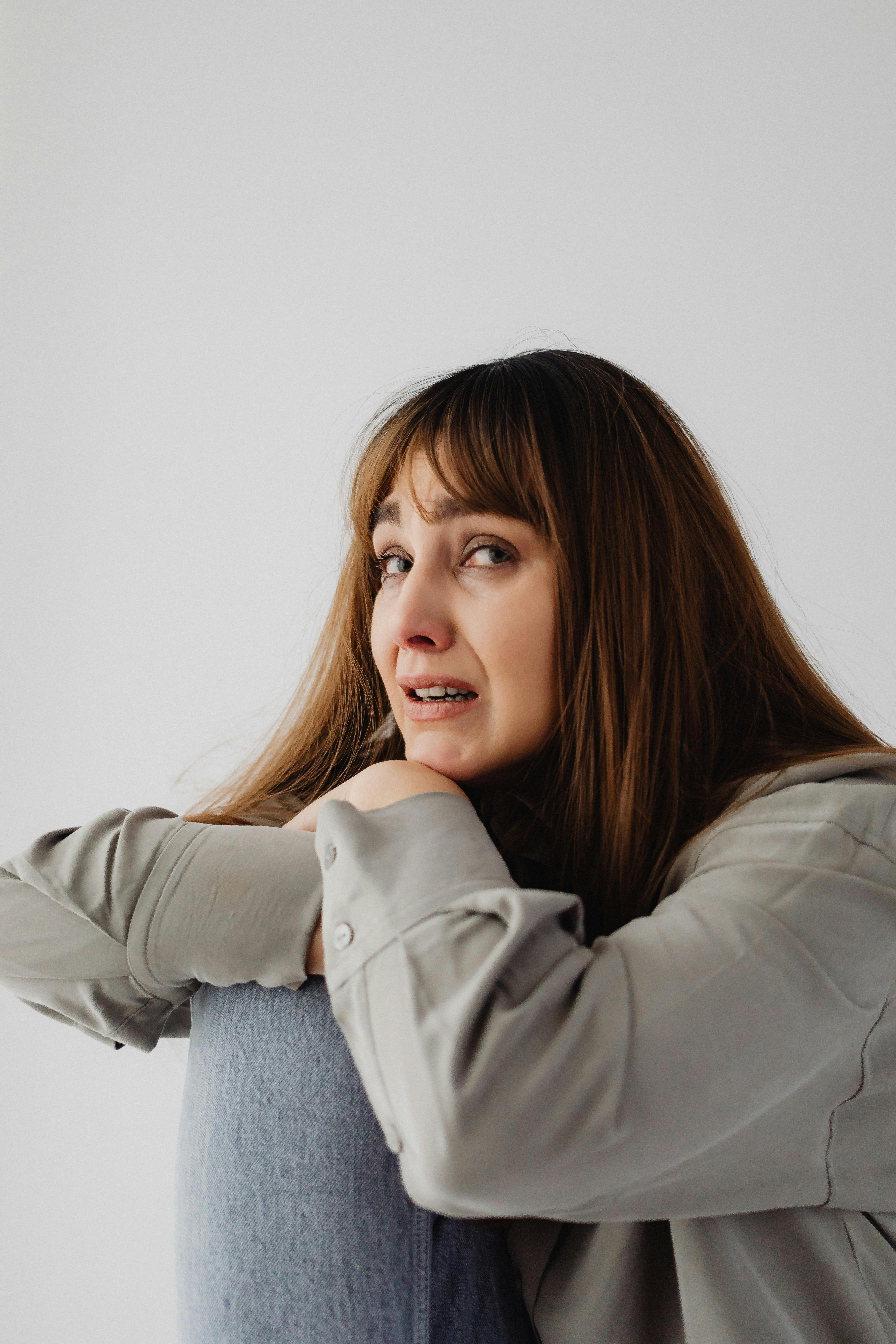 Eine emotionale Frau, die sich gegen einen Stuhl lehnt | Quelle: Pexels