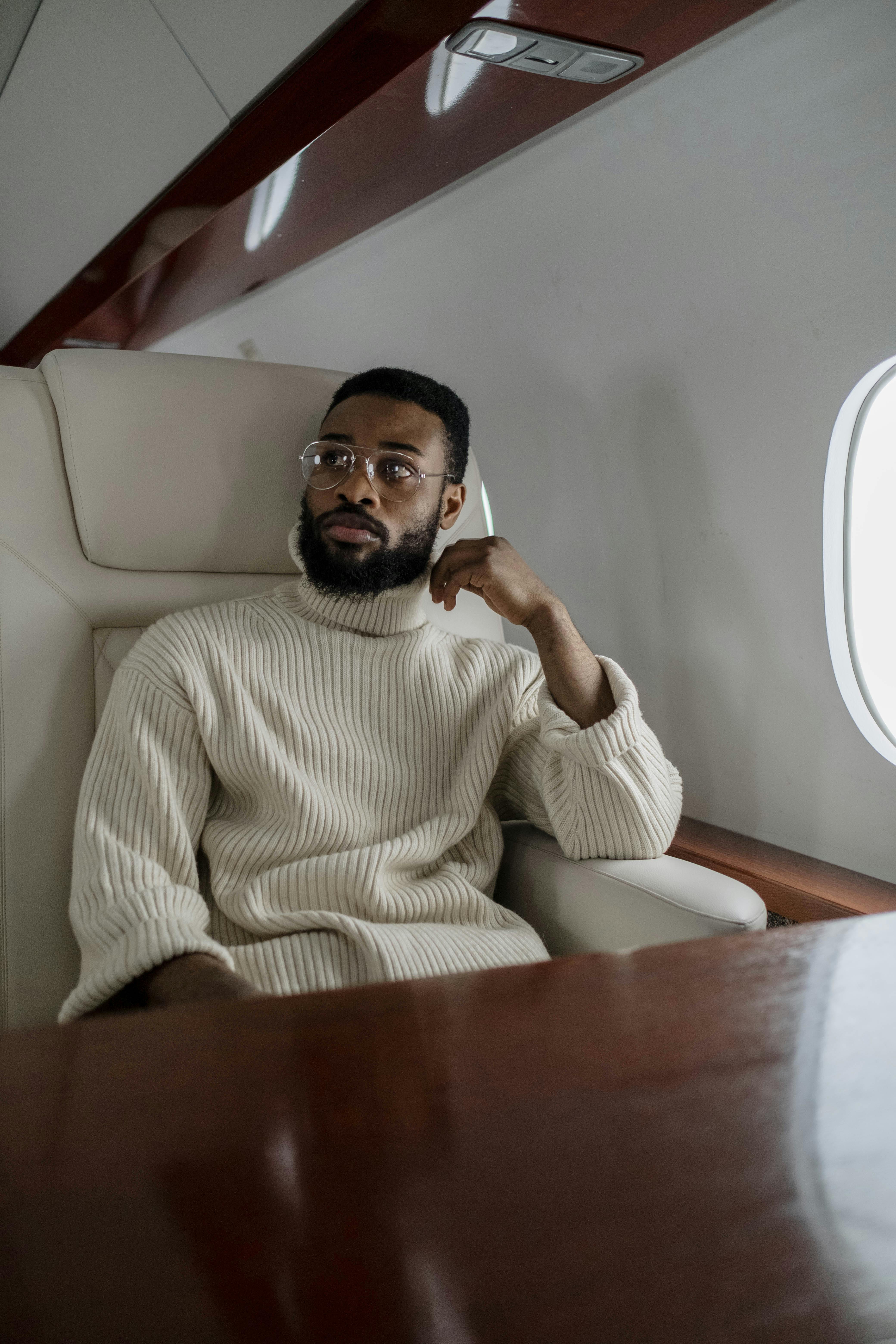 Mann im beigen Rollkragenpullover in einem Flugzeug | Quelle: Pexels