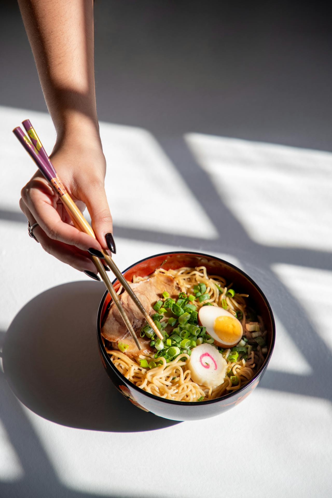Eine Frau hält Stäbchen und isst Ramen | Quelle: Pexels