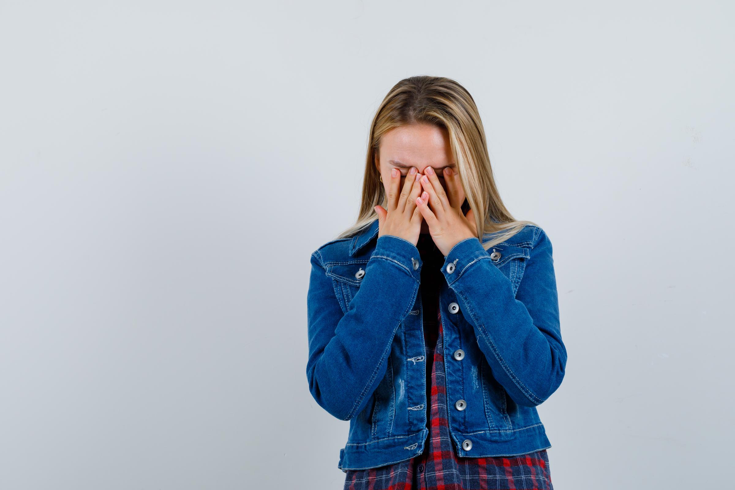 Ein junges Mädchen, das sein Gesicht mit den Händen bedeckt | Quelle: Freepik