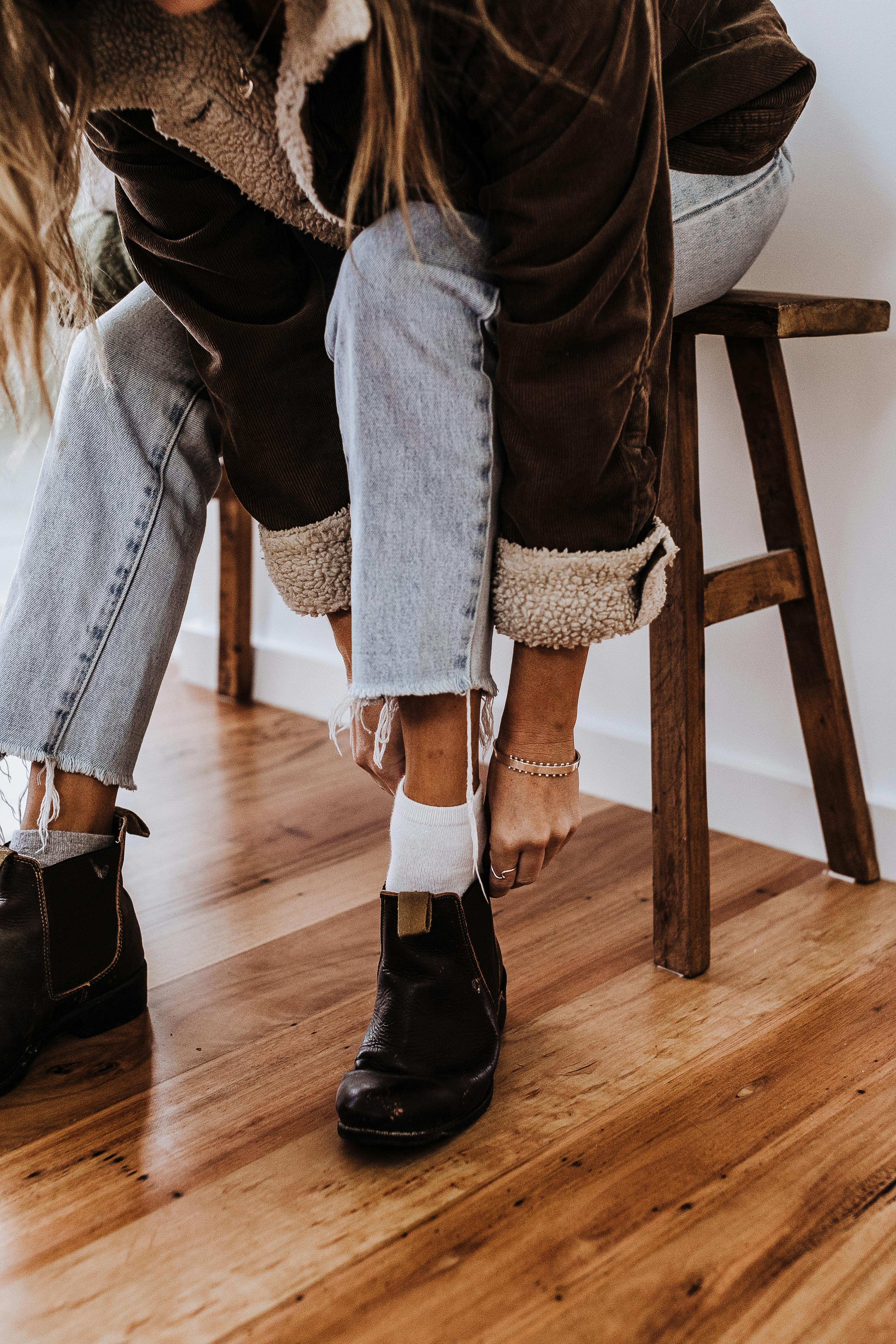 Eine Frau zieht ein Paar Stiefel an | Quelle: Pexels