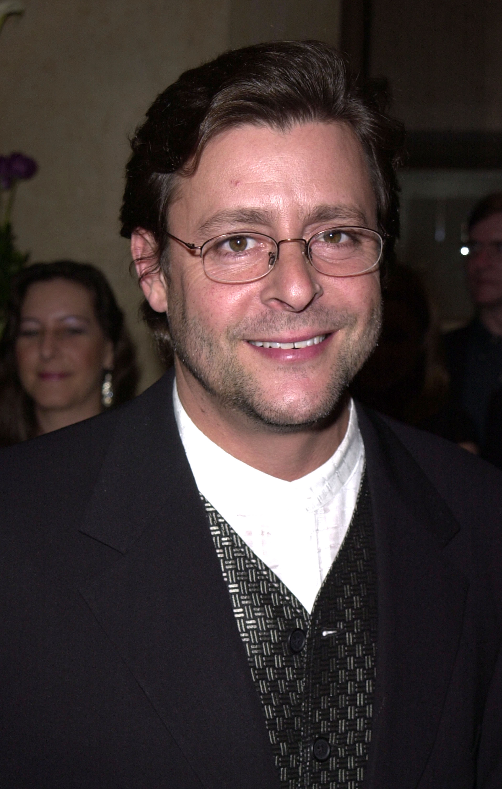 Der Schauspieler, der eine Brille mit dünnem Rahmen und eine gemusterte Weste unter einer dunklen Jacke trug, schenkte den Anwesenden bei der 15. Verleihung der Genesis Awards am 10. März 2001 ein warmes Lächeln. | Quelle: Getty Images