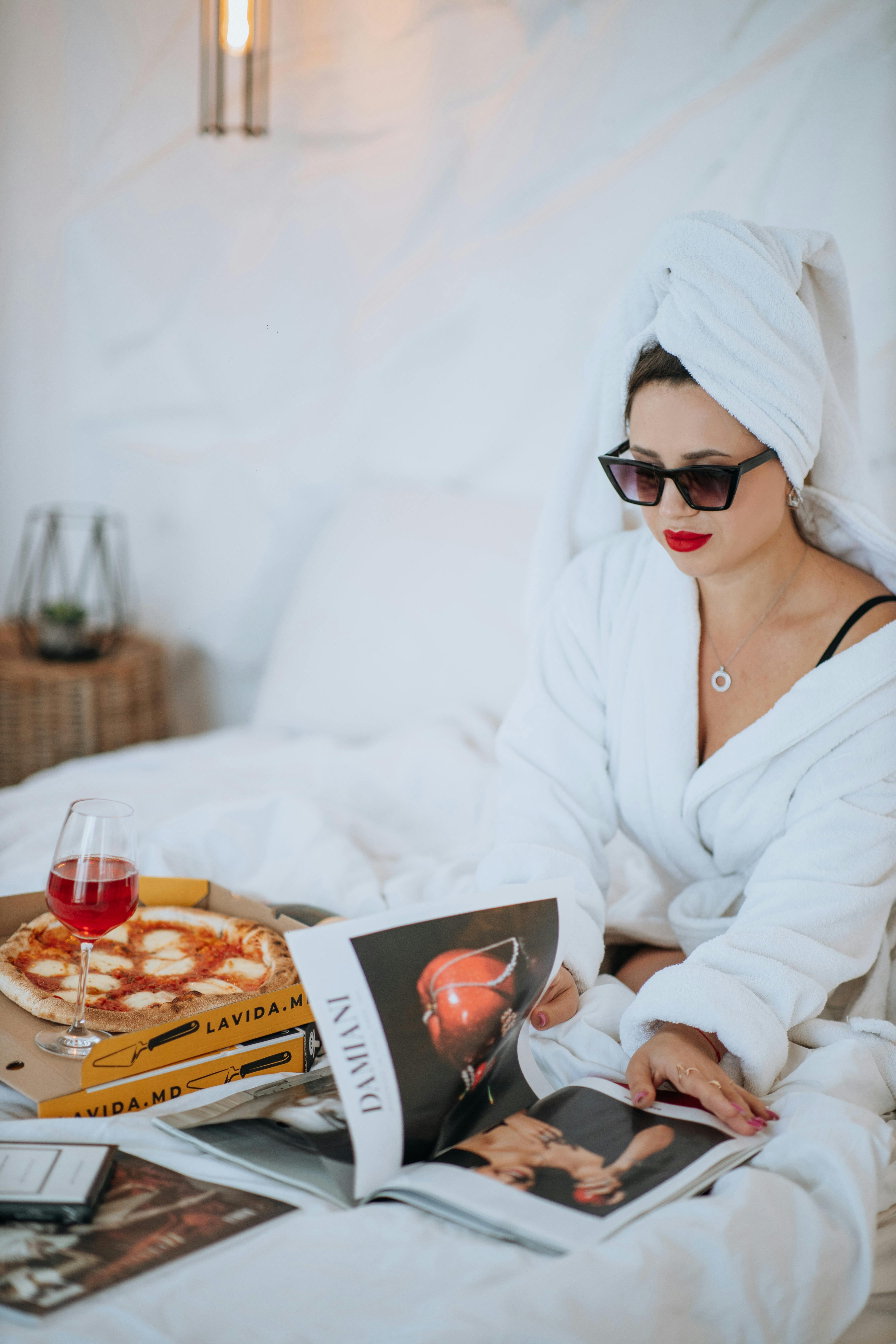 Eine Frau im Bademantel beim Pizzaessen im Bett | Quelle: Pexels