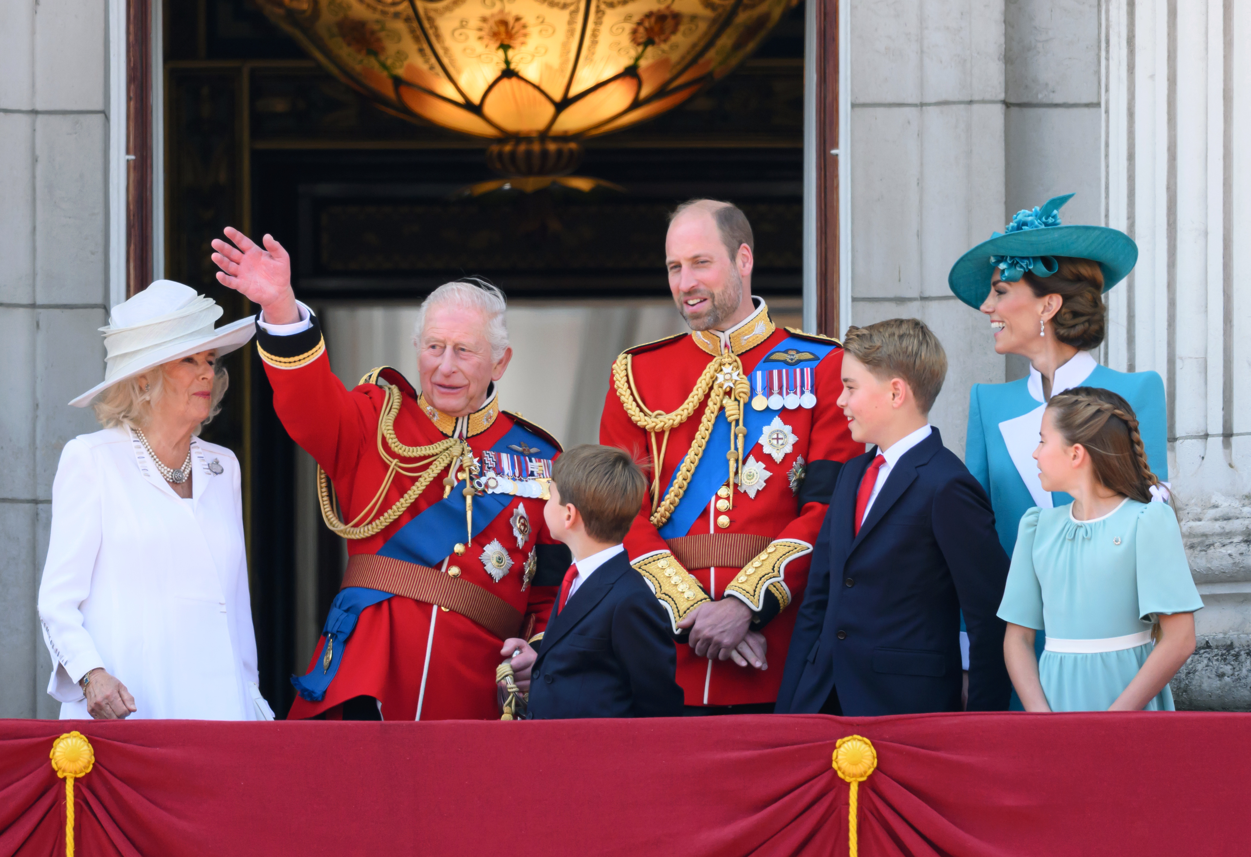 König Charles III. winkt dem englischen Volk zu, während Königin Camilla, Prinz William, die Prinzen Louis und George sowie die Prinzessinnen Catherine und Charlotte ihn auf dem Balkon des Buckingham Palace beobachten.