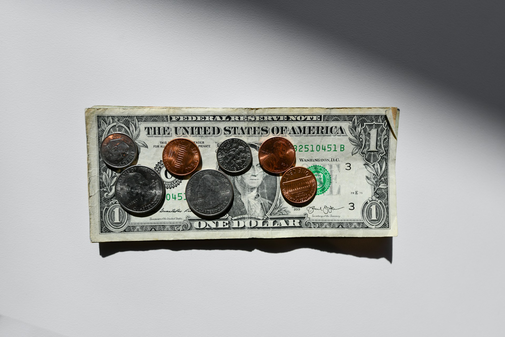 Münzen auf einem dünnen Stapel von Dollarscheinen | Quelle: Unsplash