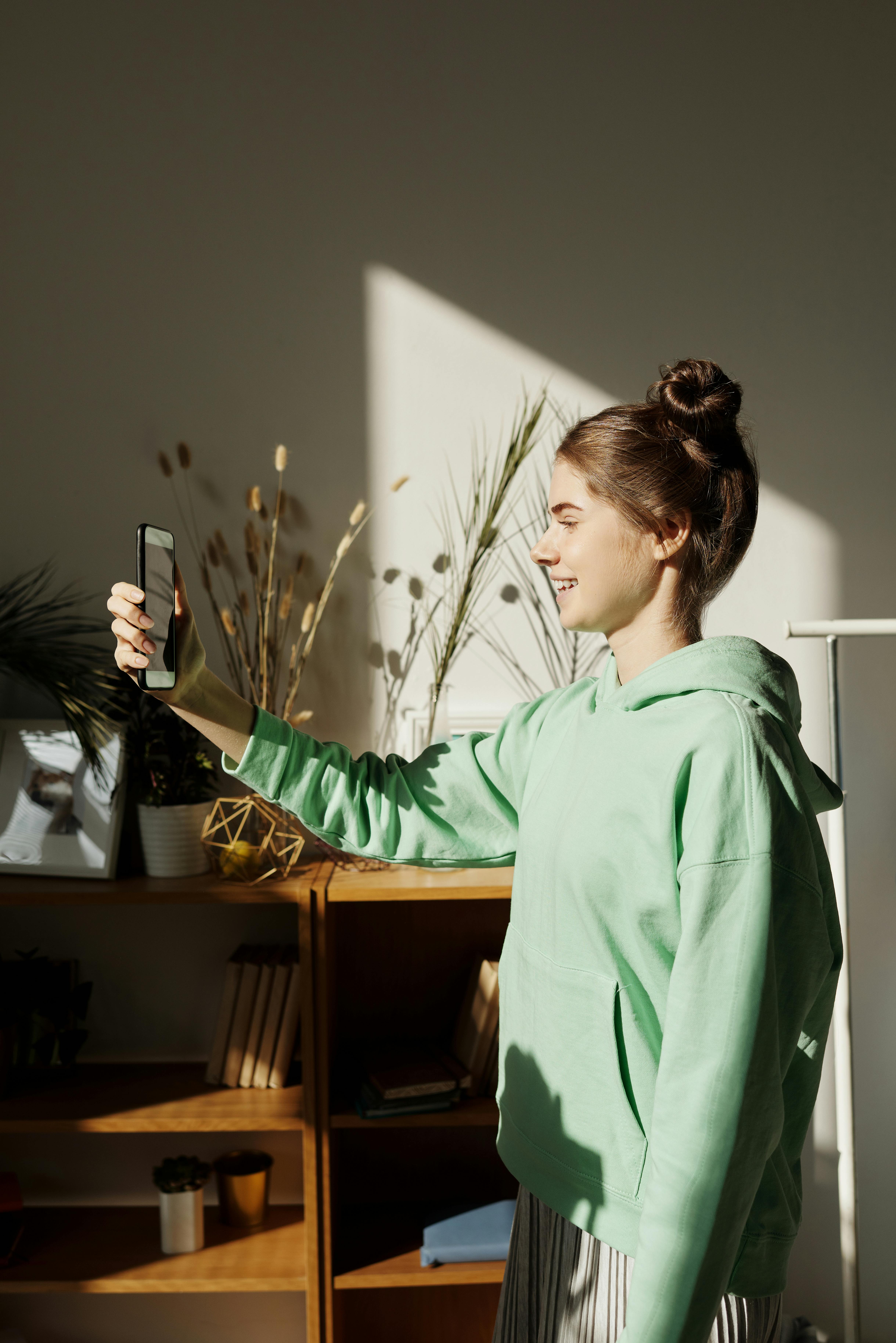 Ein Mädchen, das lacht, während es mit seinem Handy aufnimmt | Quelle: Pexels