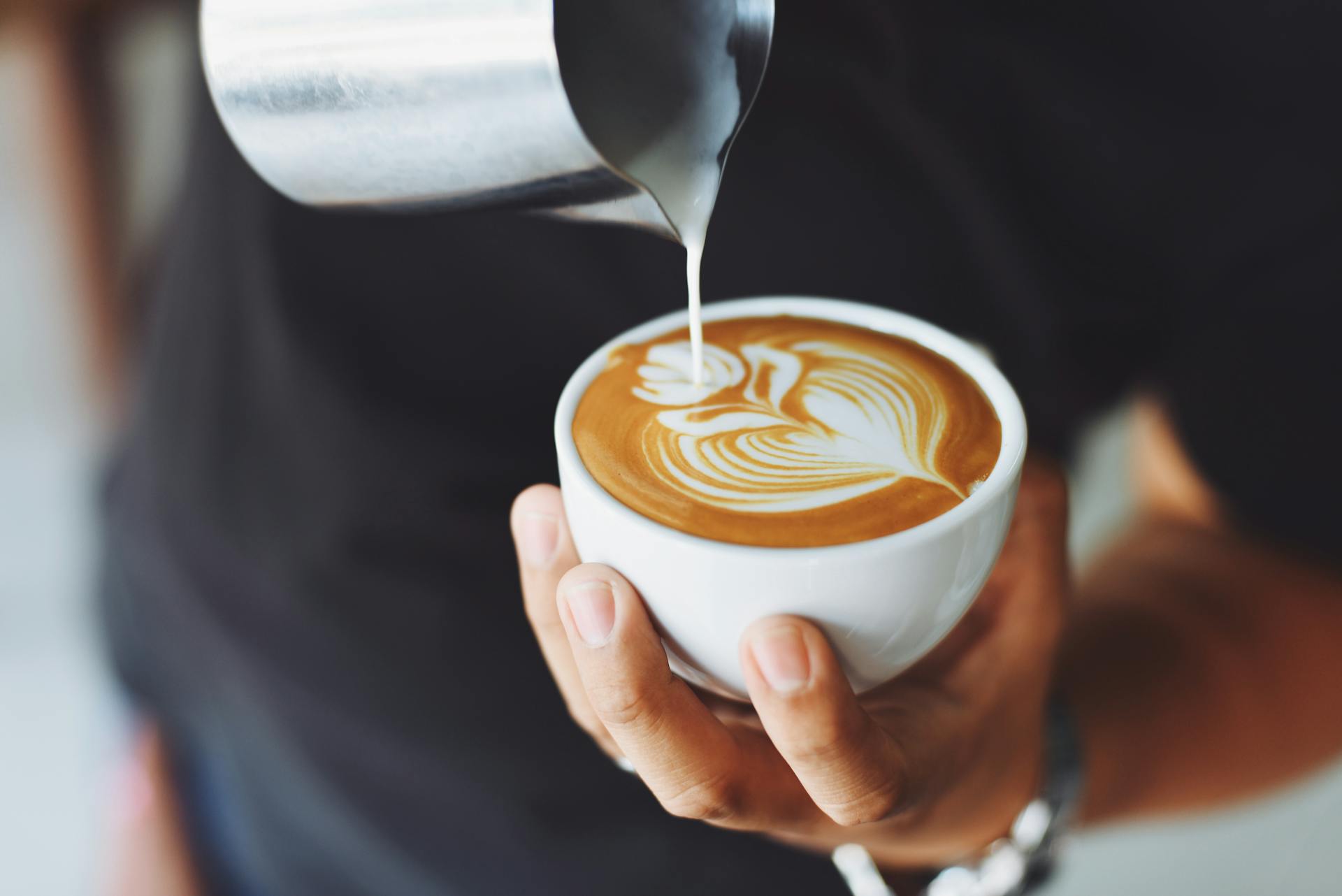 Ein Mann gießt Sahne in eine Tasse Kaffee | Quelle: Pexels