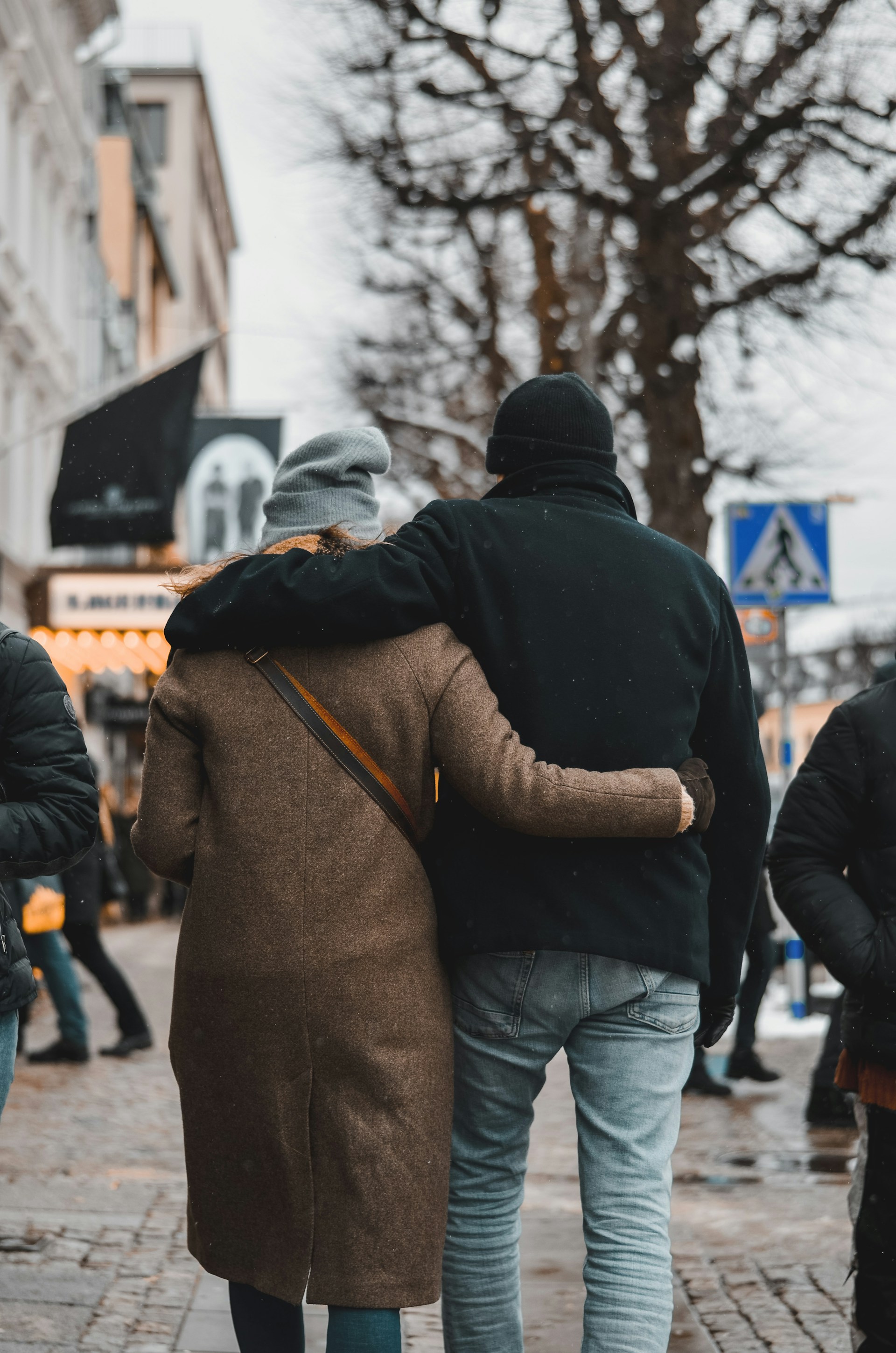 Ein Paar, das sich umarmt und auf der Straße spazieren geht | Quelle: Unsplash