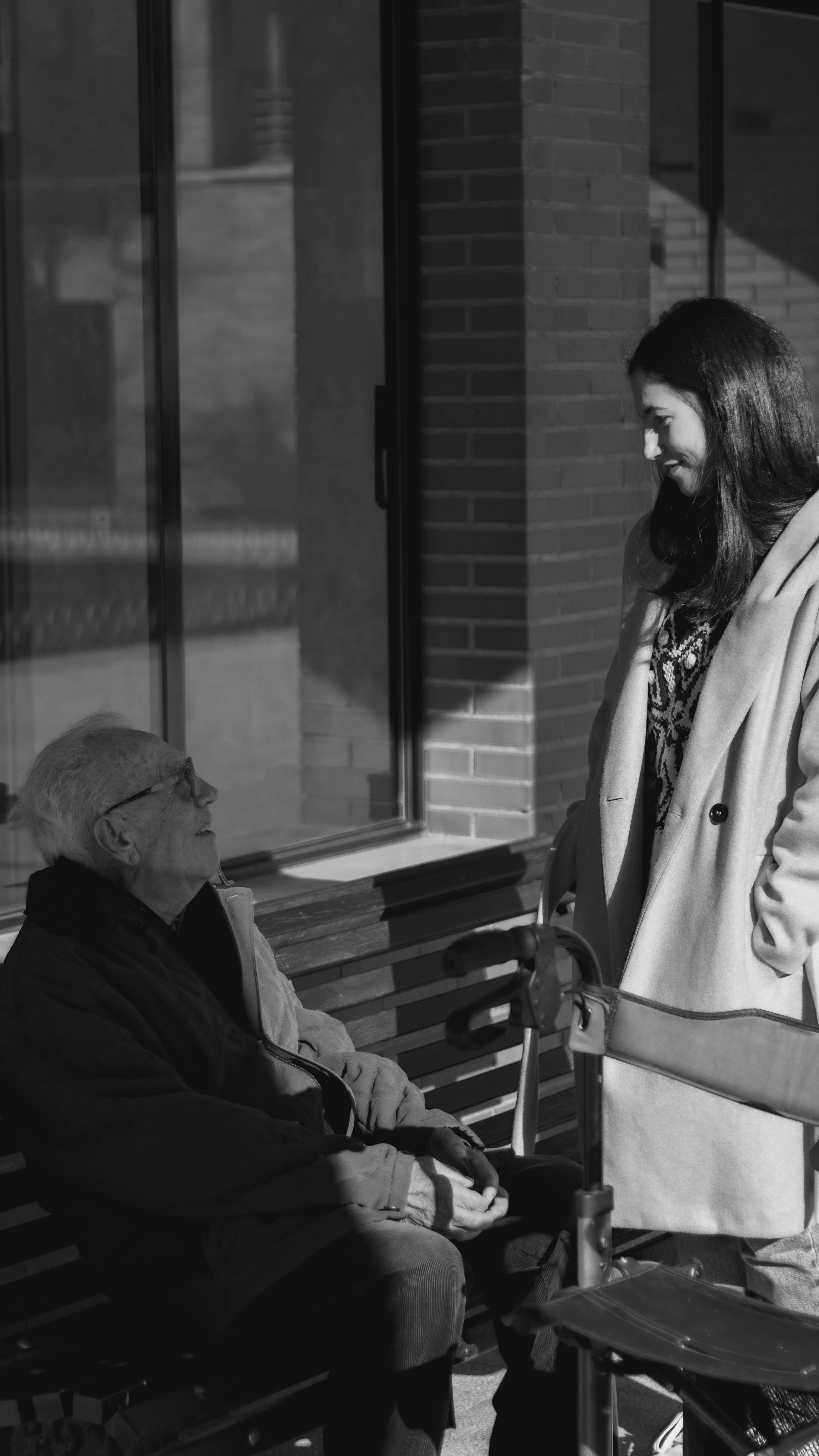 Älterer Mann sitzt auf einer Bank und spricht mit einer Frau | Quelle: Unsplash