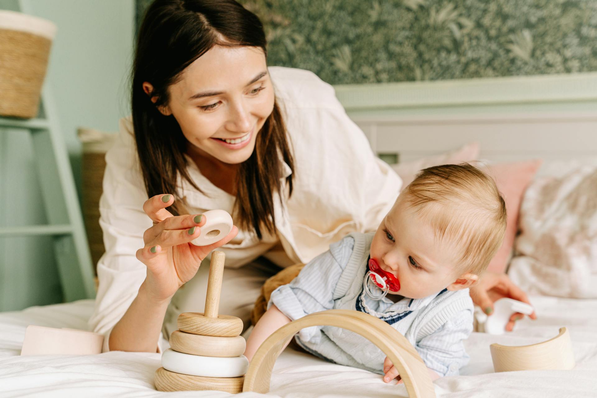 Eine Frau spielt mit ihrem Baby auf einem Bett | Quelle: Pexels