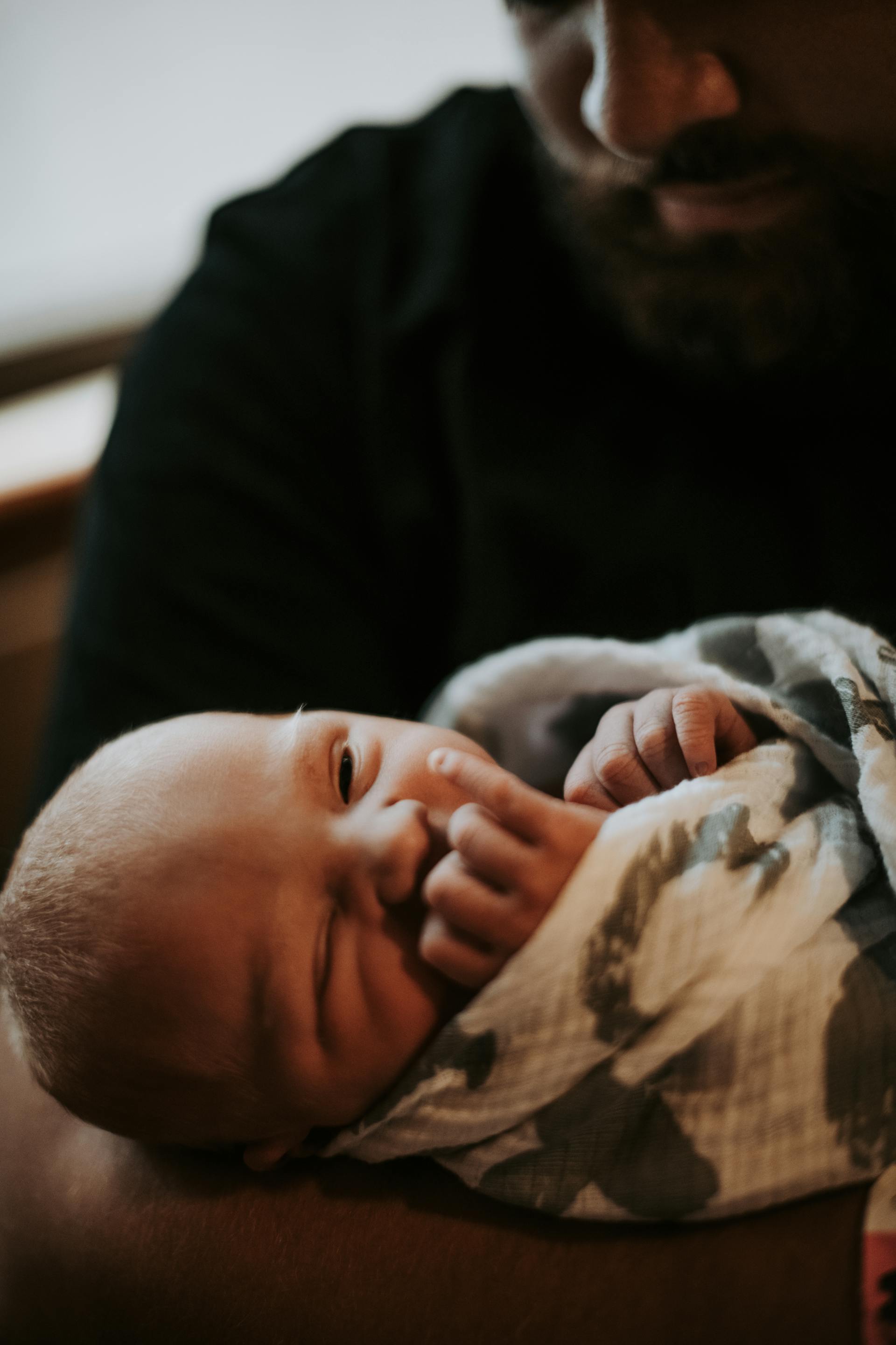 Ein in eine Decke gewickeltes Baby wird von einem Mann gehalten | Quelle: Pexels