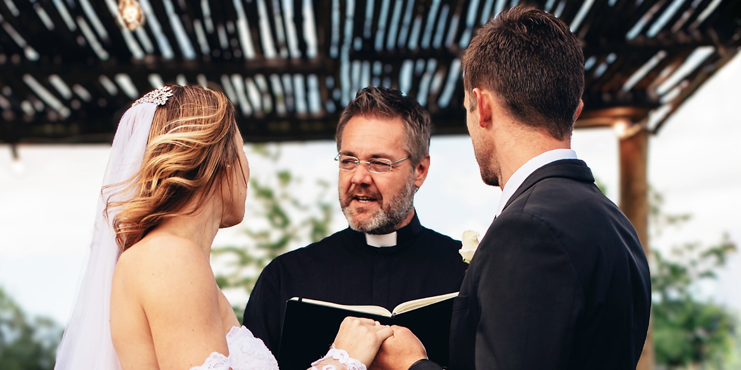 Eine Braut und ein Bräutigam vor einem Priester | Quelle: Shutterstock