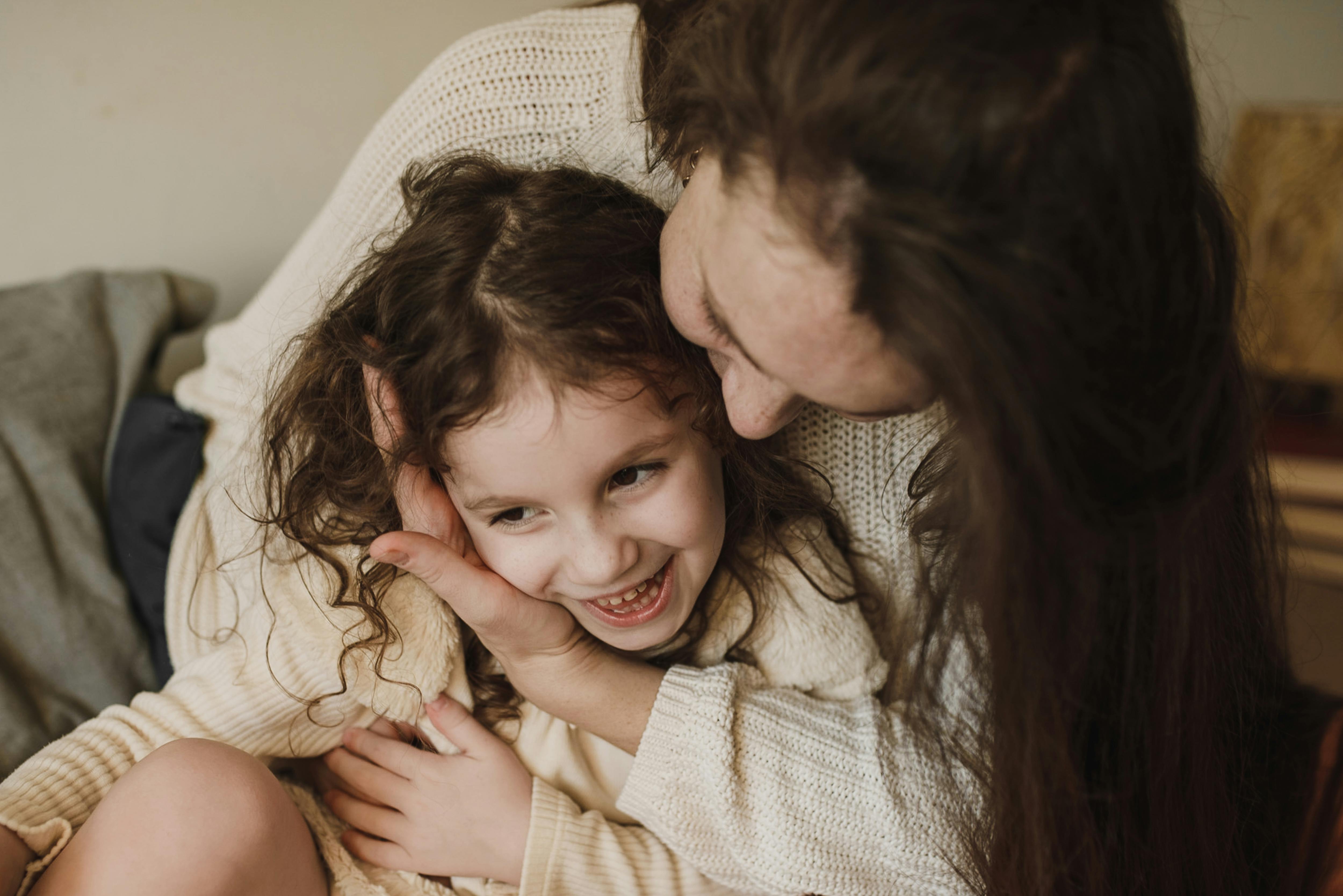 Ein glückliches Mädchen, das auf dem Schoß seiner Mutter sitzt | Quelle: Pexels
