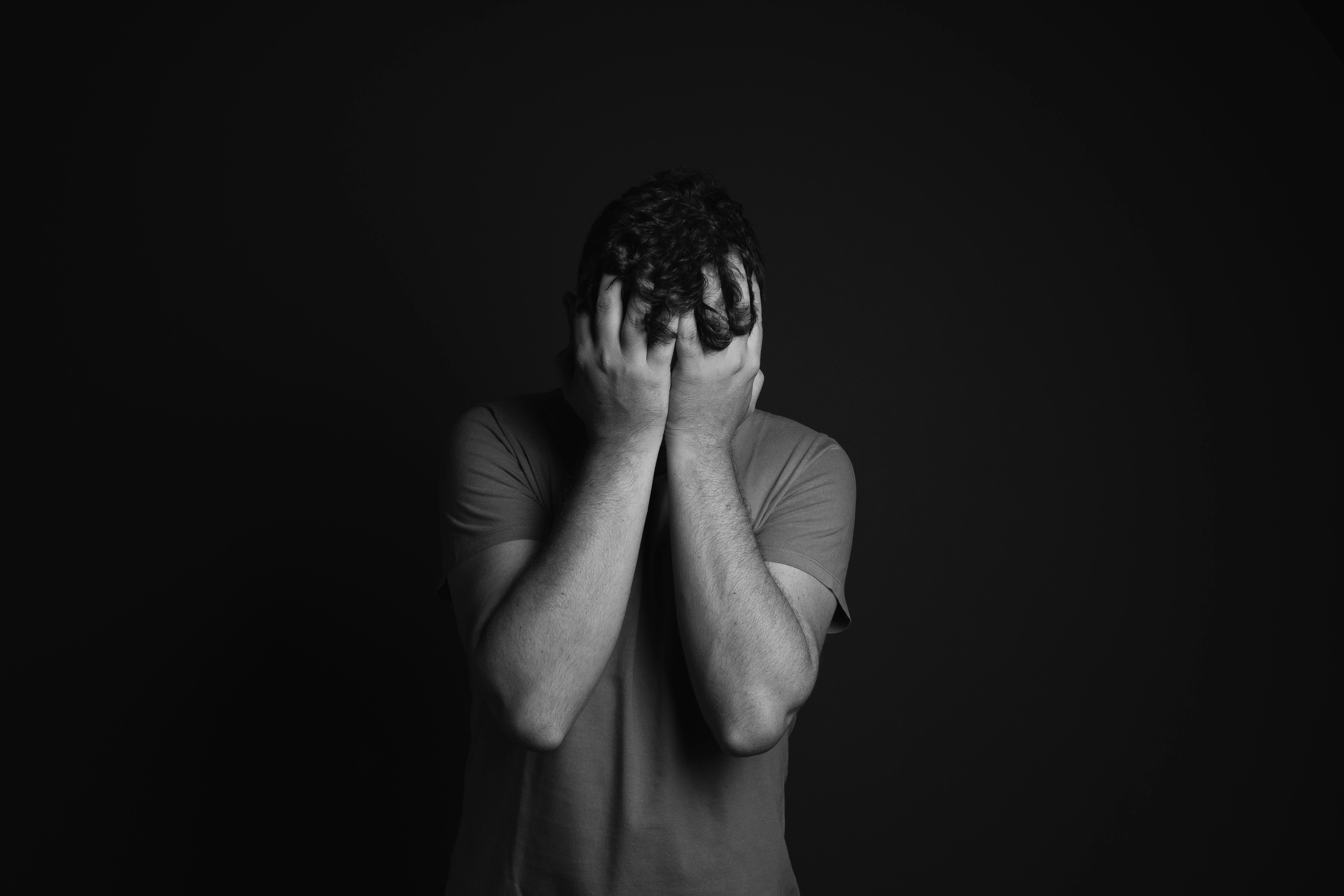 Ein trauriger Mann, der sein Gesicht bedeckt | Quelle: Pexels