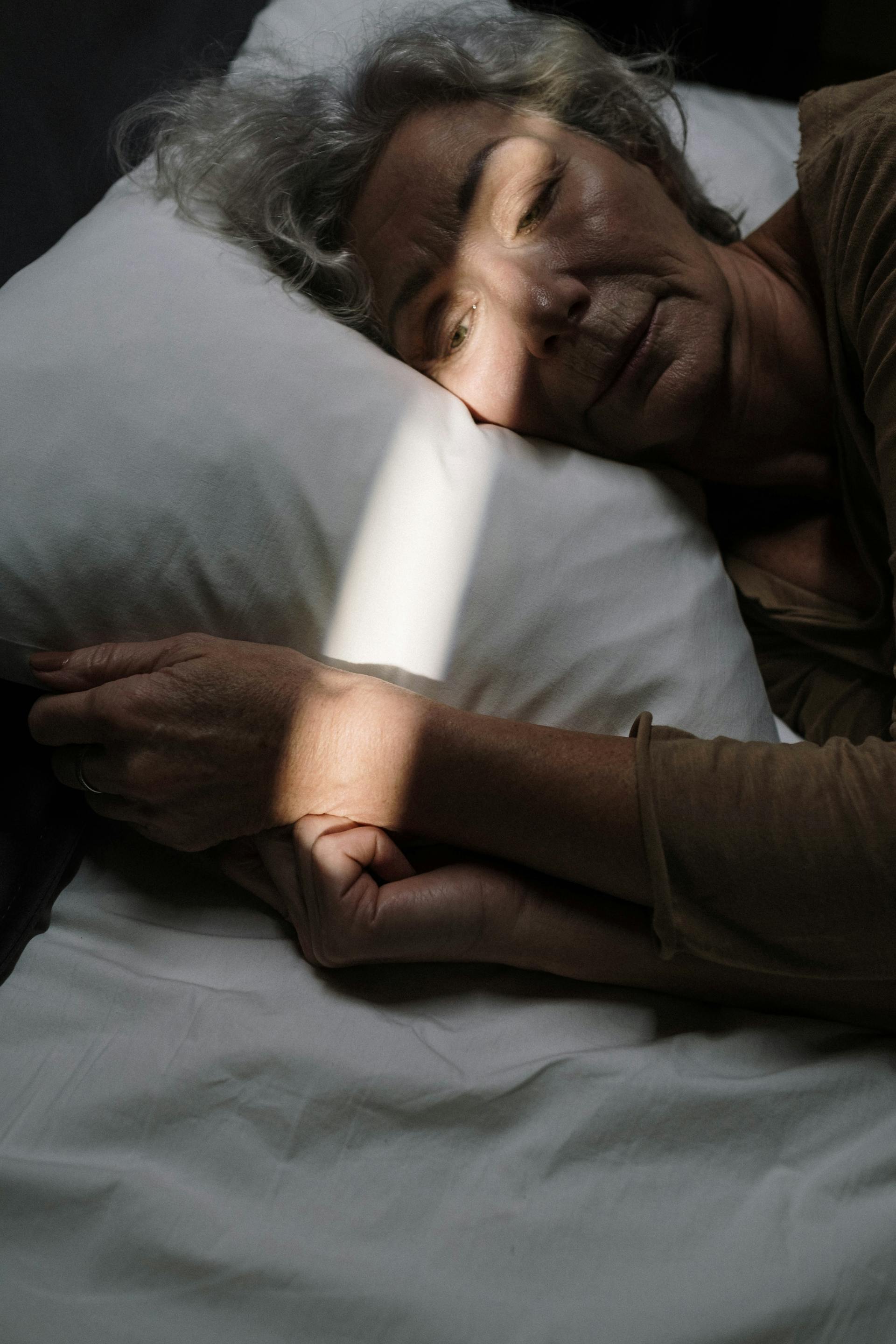 Eine traurige ältere Frau, die wach im Bett liegt | Quelle: Pexels