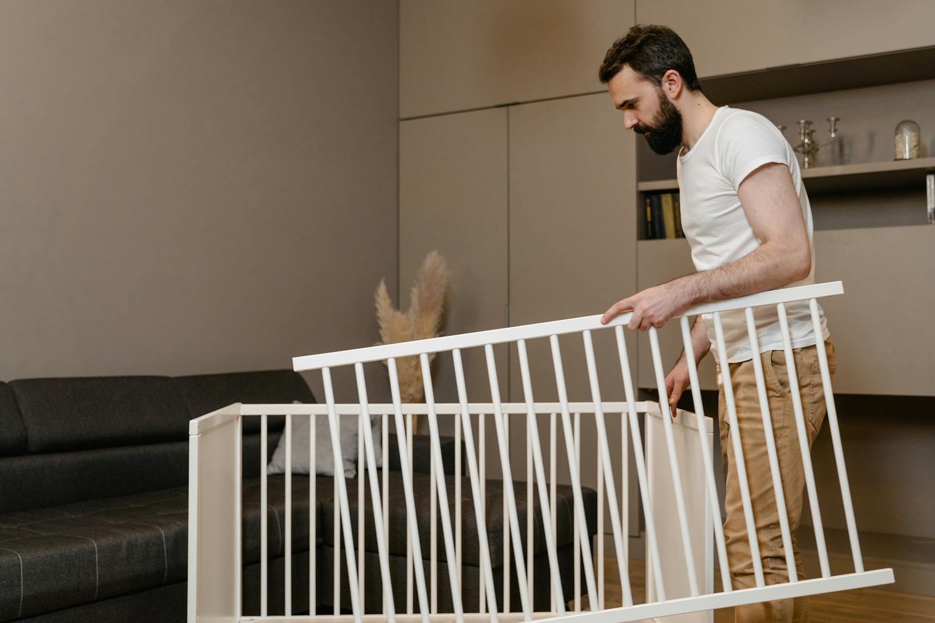 Mann mit Teilen eines zerlegten Babybettes | Quelle: Pexels
