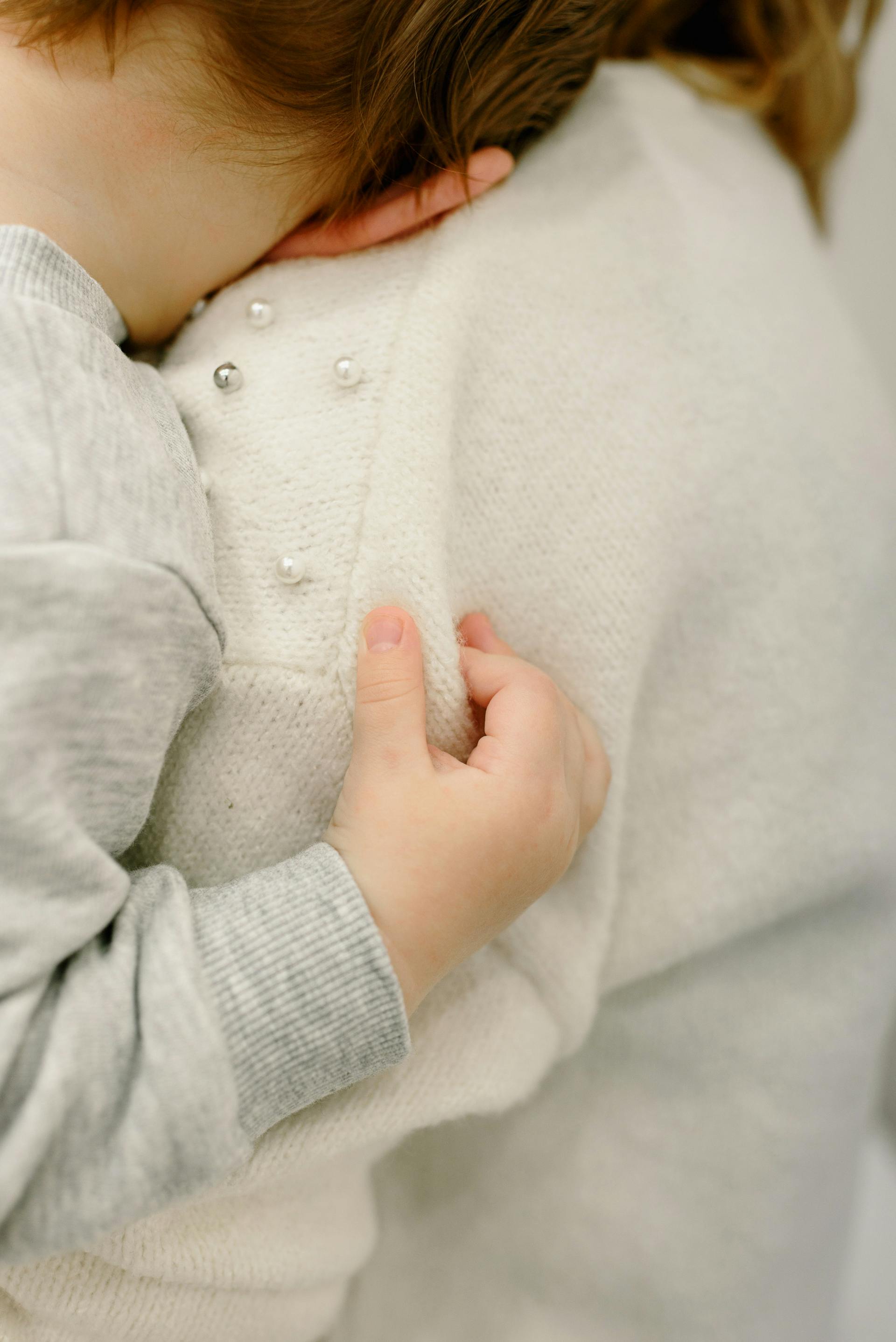 Ein Kleinkind, das sich an die Schulter seiner Mutter lehnt | Quelle: Pexels